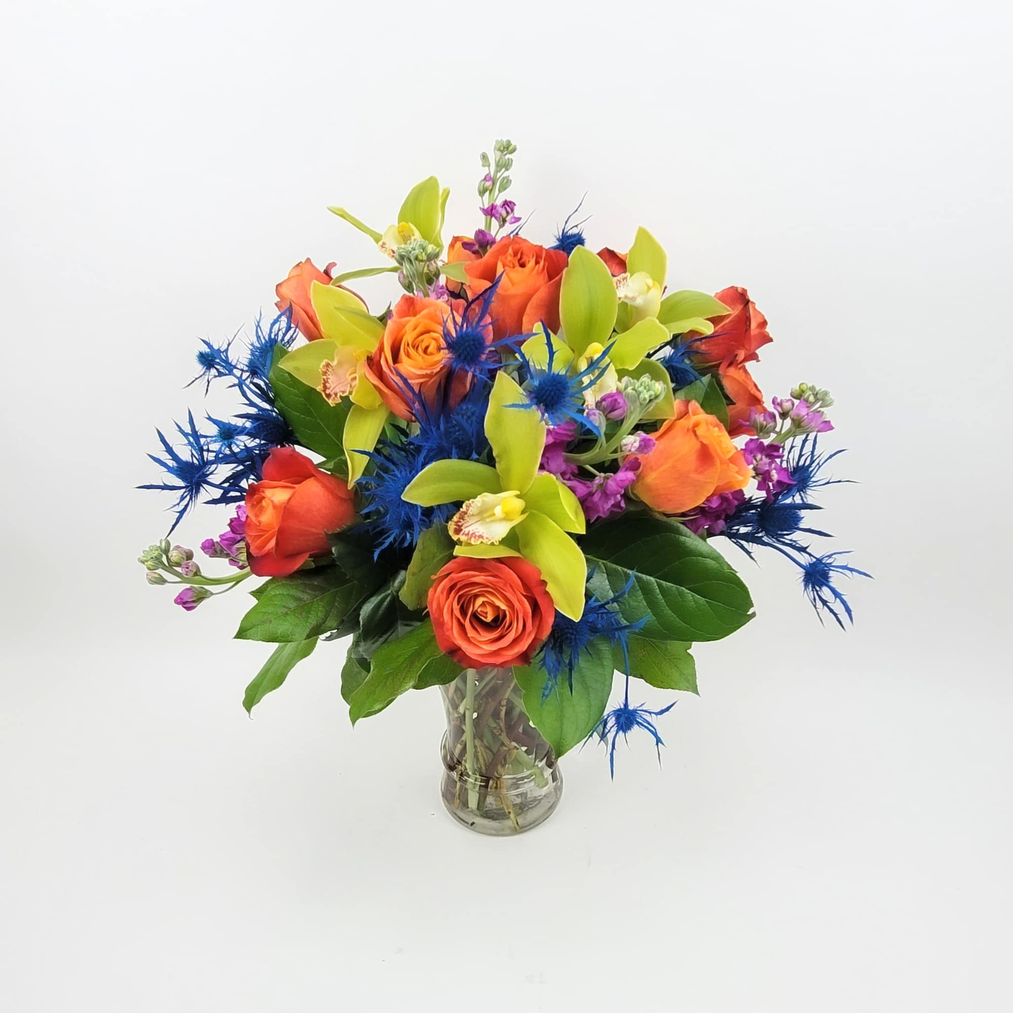 An arrangement in a clear vase made with roses, eryngium, mix flowers