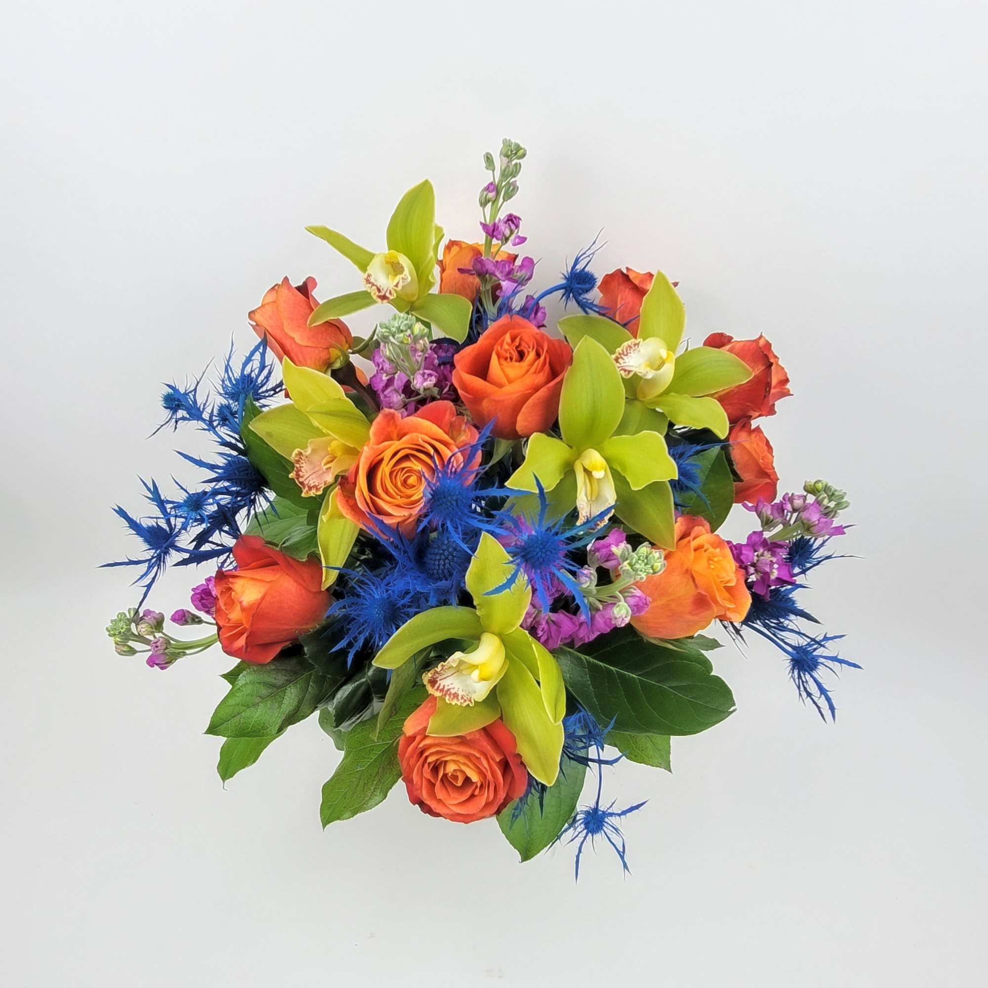 An arrangement in a clear vase made with roses, eryngium, mix flowers