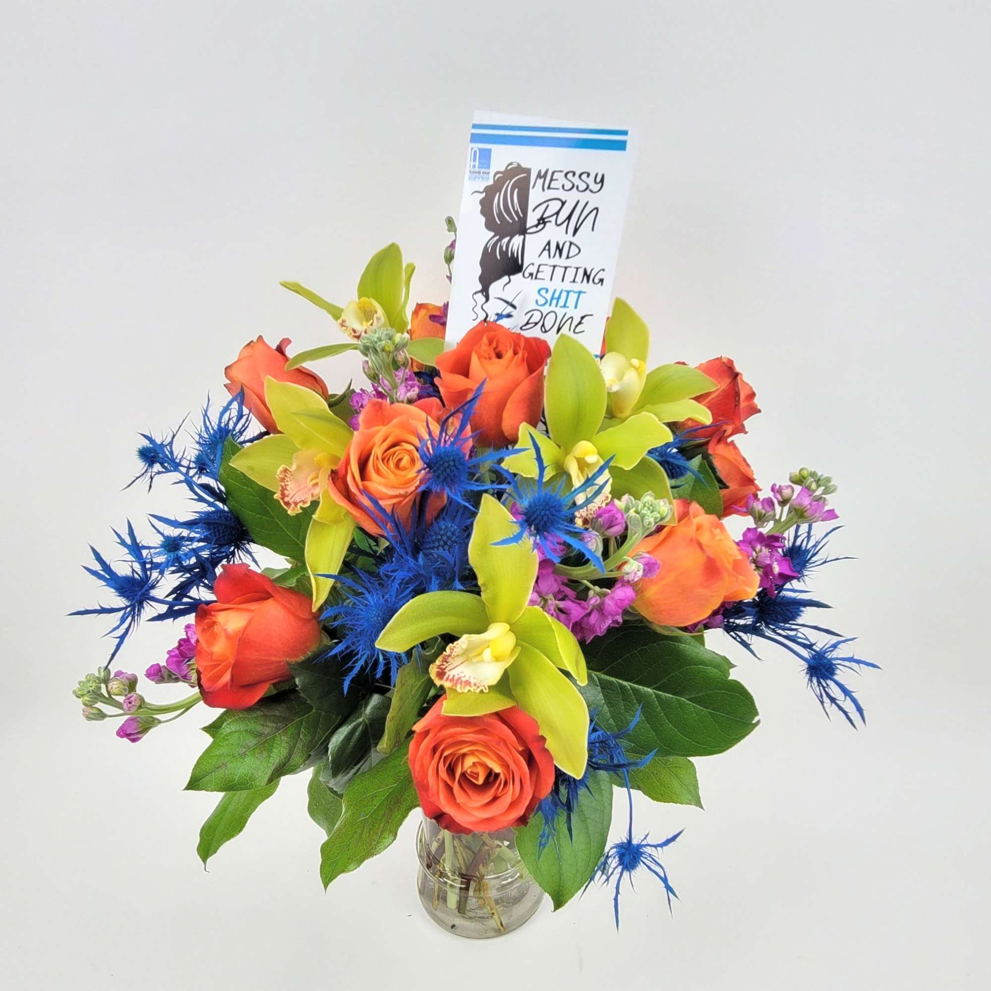 An arrangement in a clear vase made with roses, eryngium, mix flowers