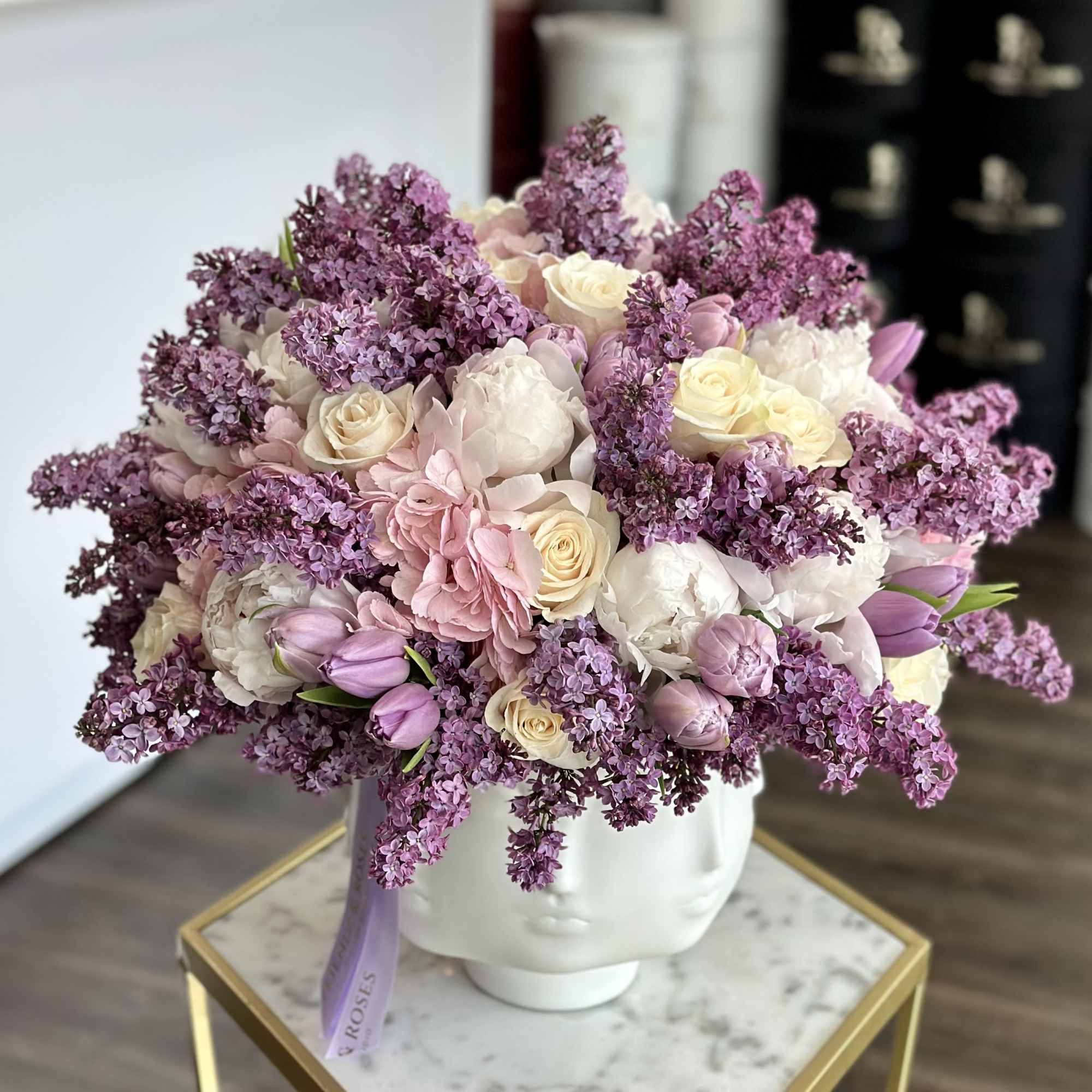 A charming floral composition featuring lilacs, tulips, peonies, and roses, artfully gathered