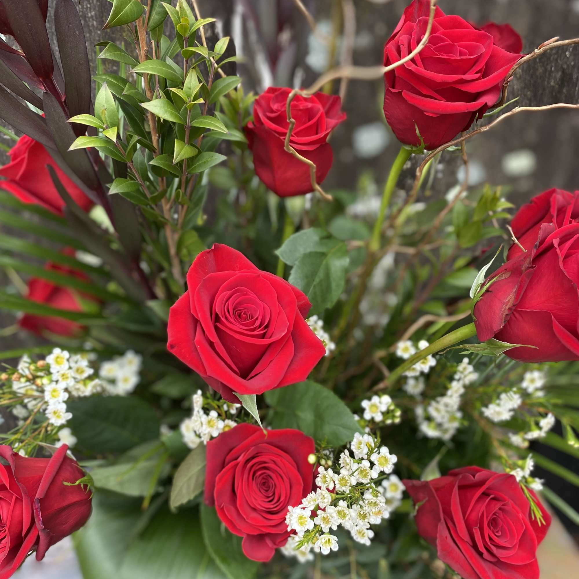 Twelve roses arranged in a tall glass vase. 
To request another color