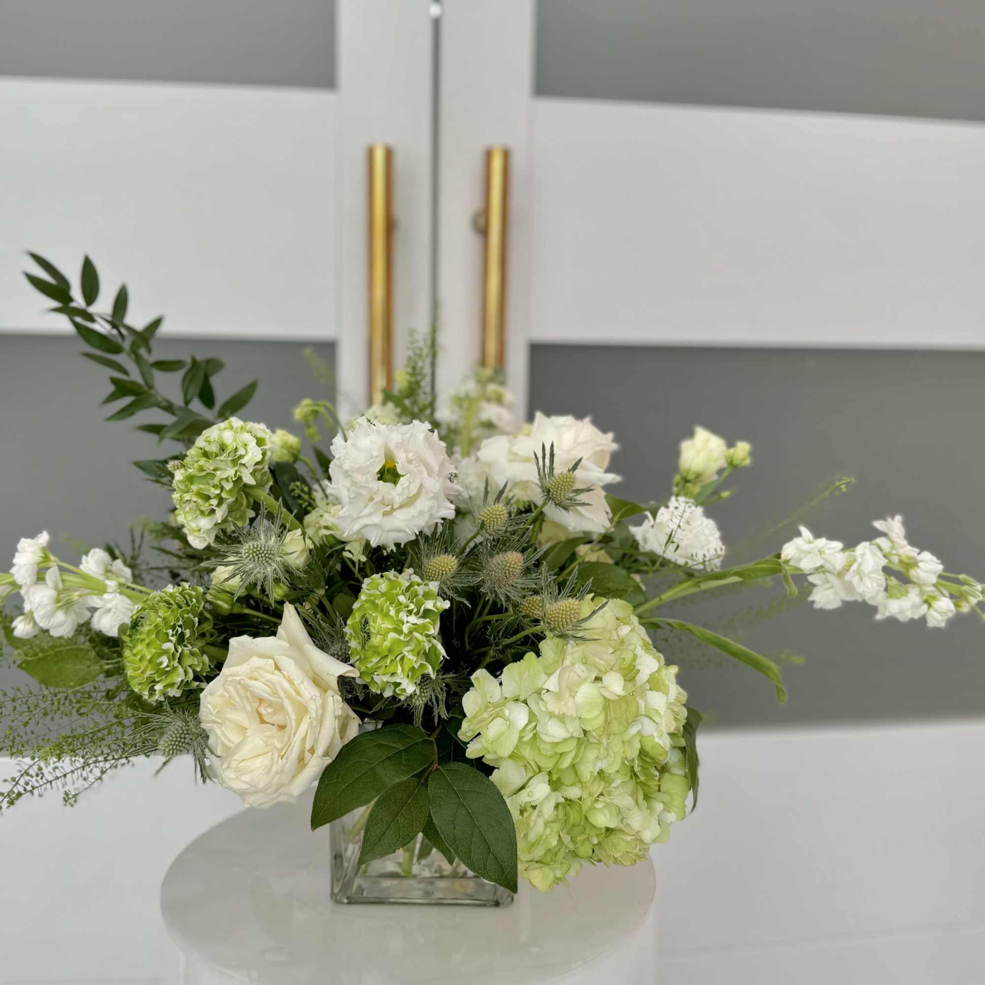 Assortment  of white and a mix of greenery on a clear