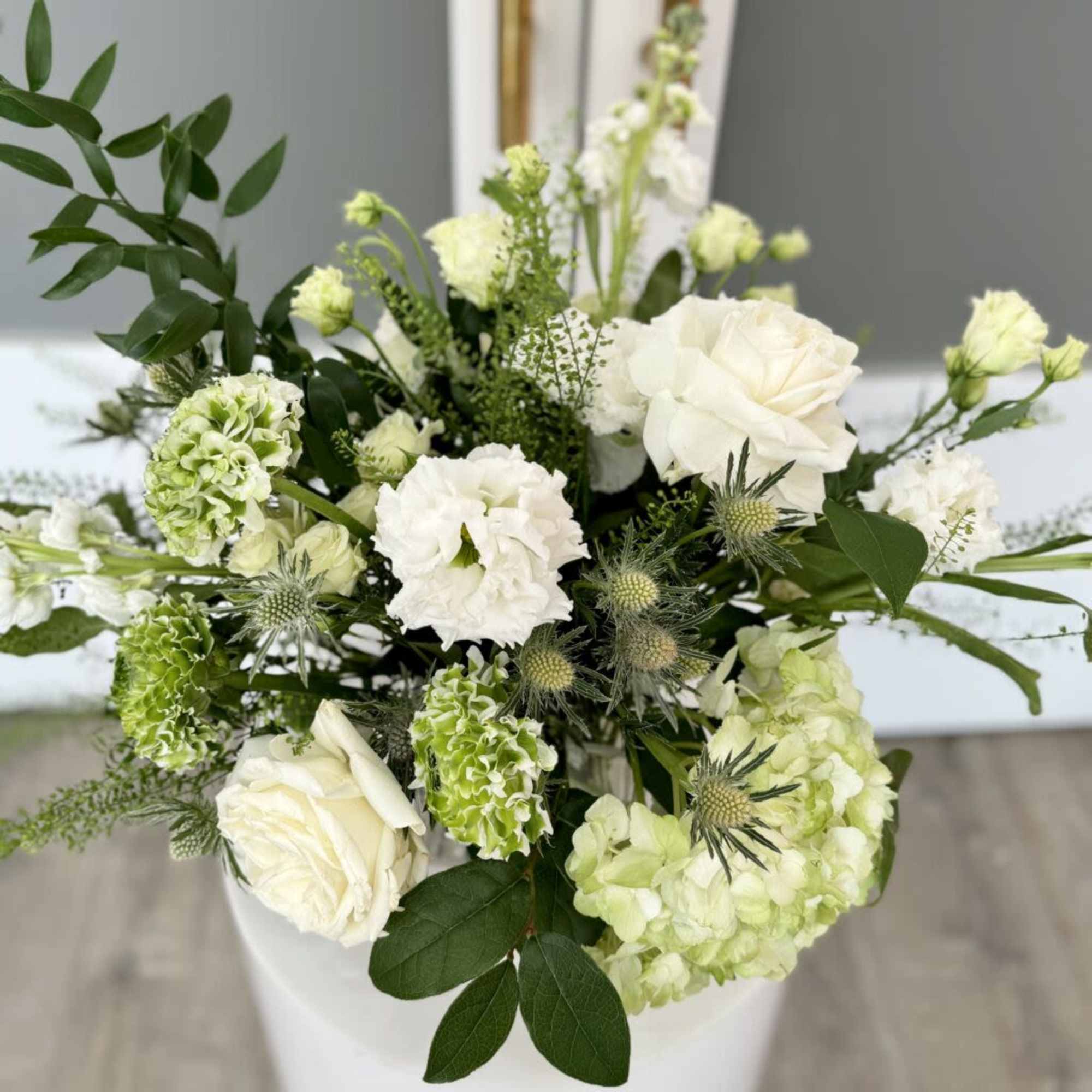 Assortment  of white and a mix of greenery on a clear