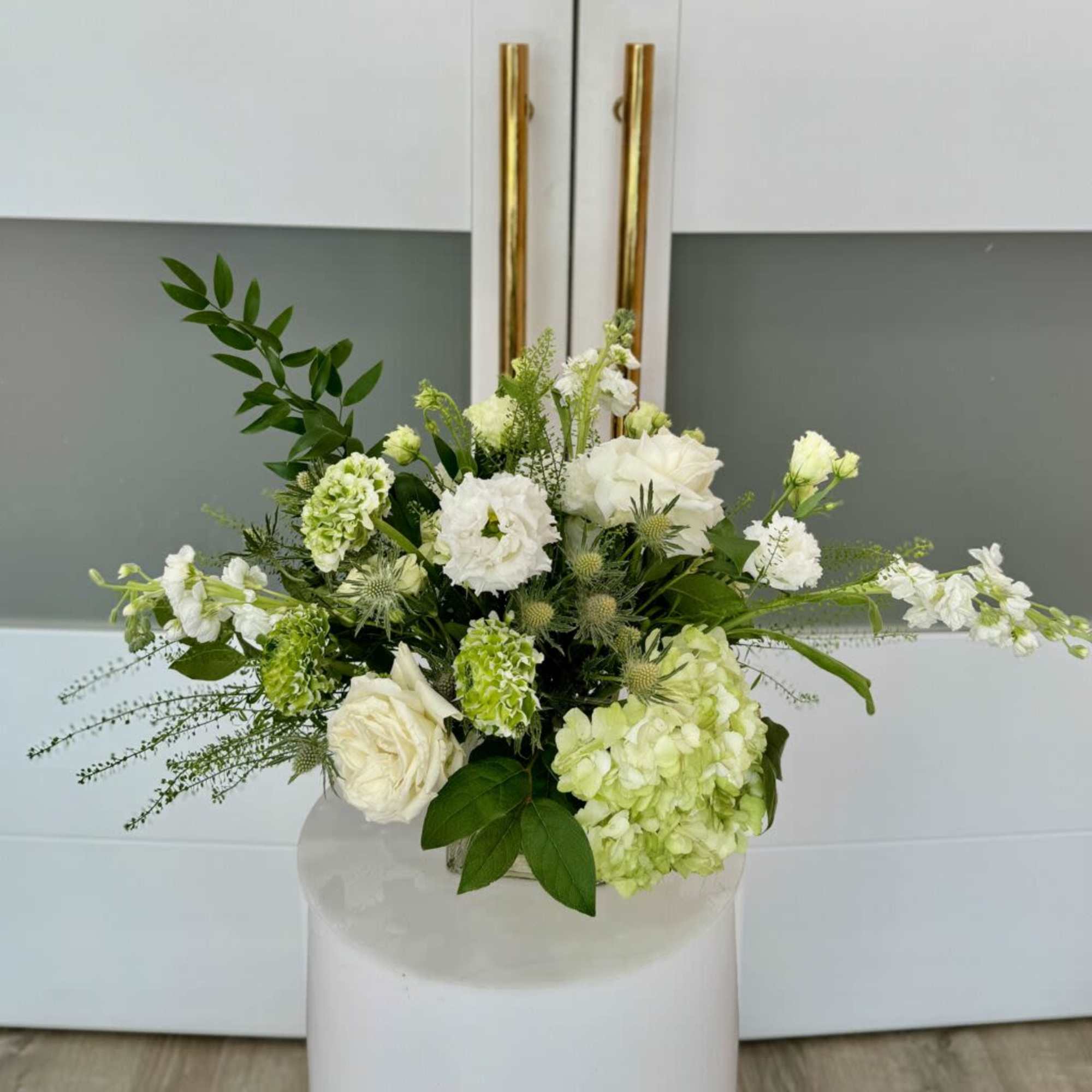 Assortment  of white and a mix of greenery on a clear