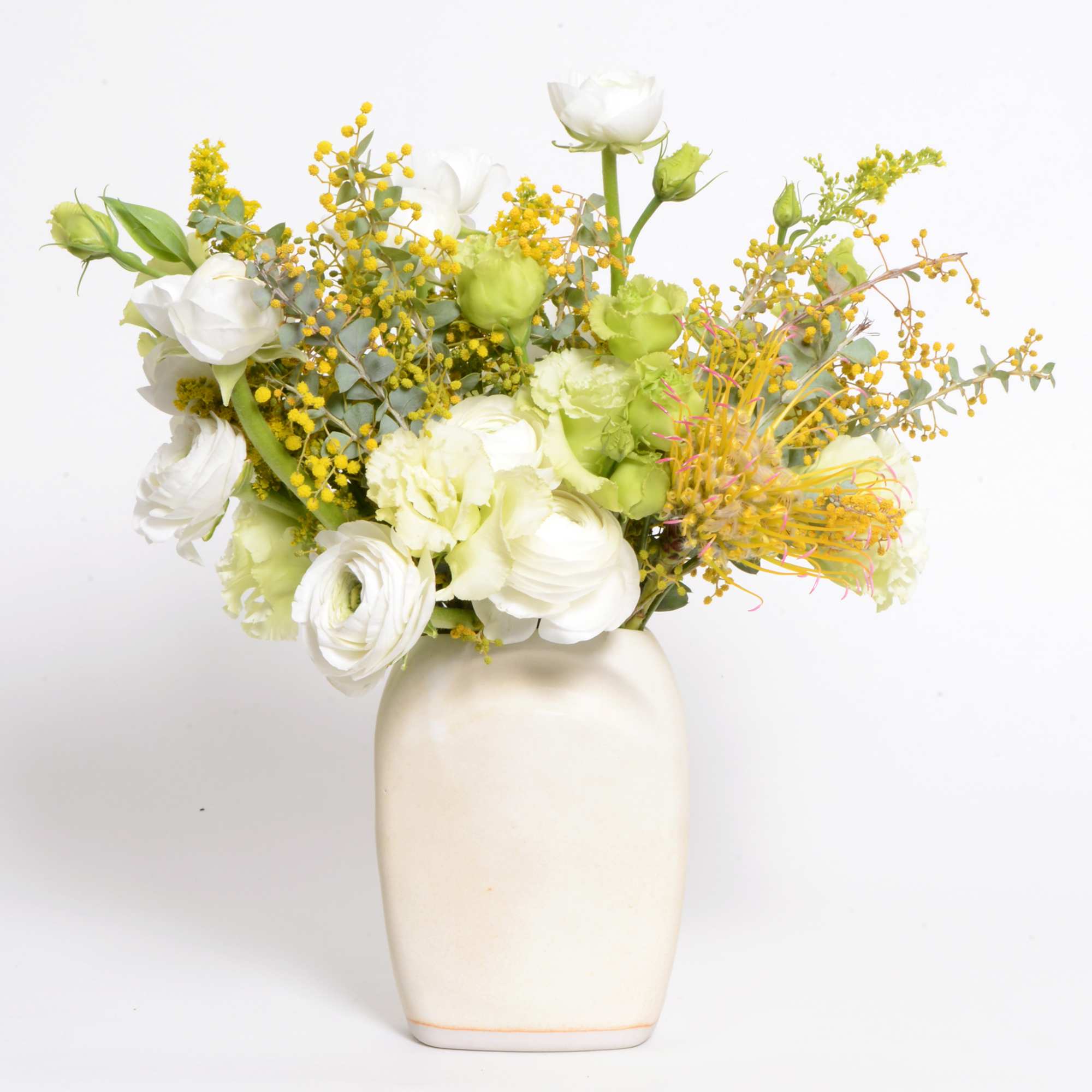An arrangement of cream and white seasonal flowers in a handmade ceramic
