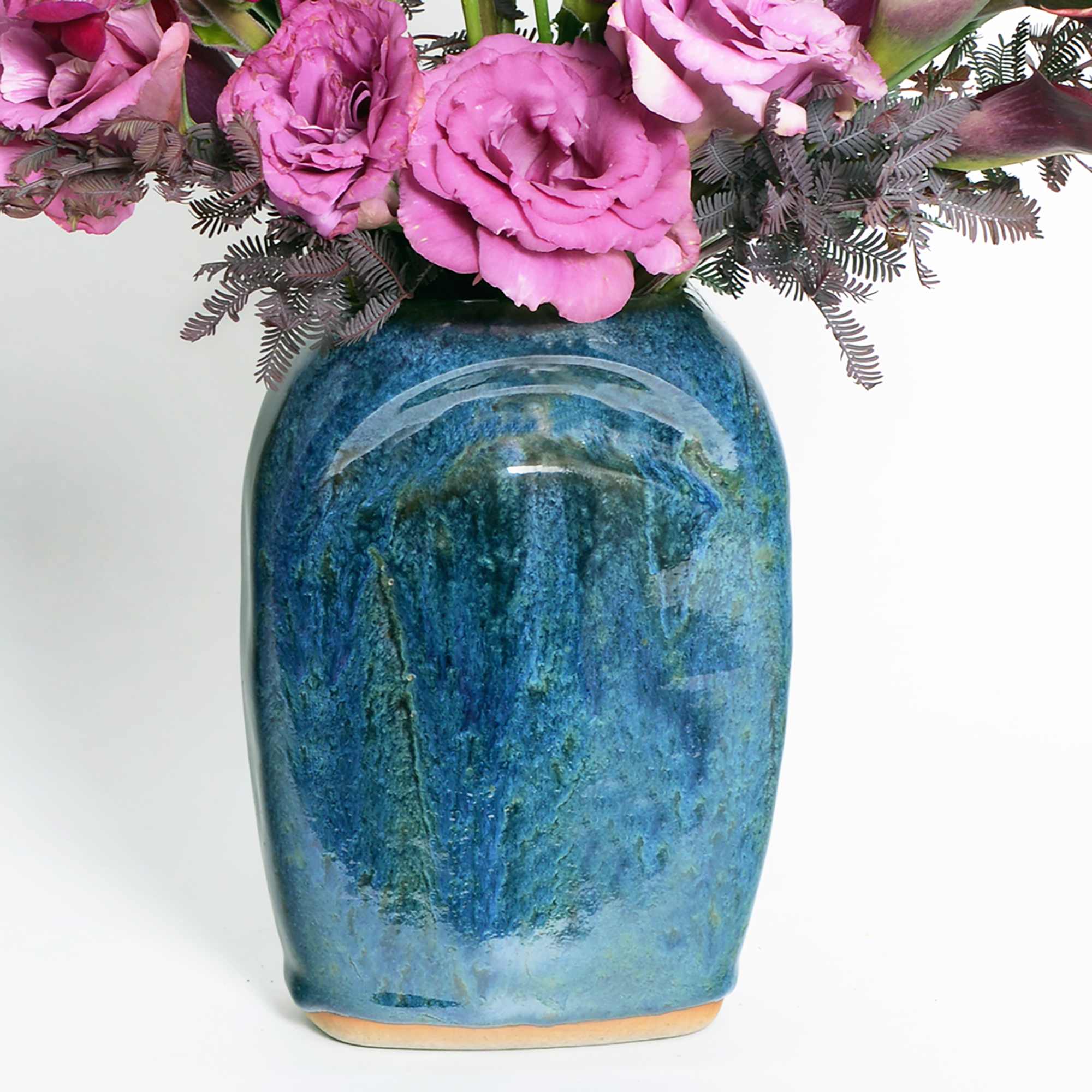 An arrangement of burgundy calla lilies, purple lisianthus and purple snapdragons in