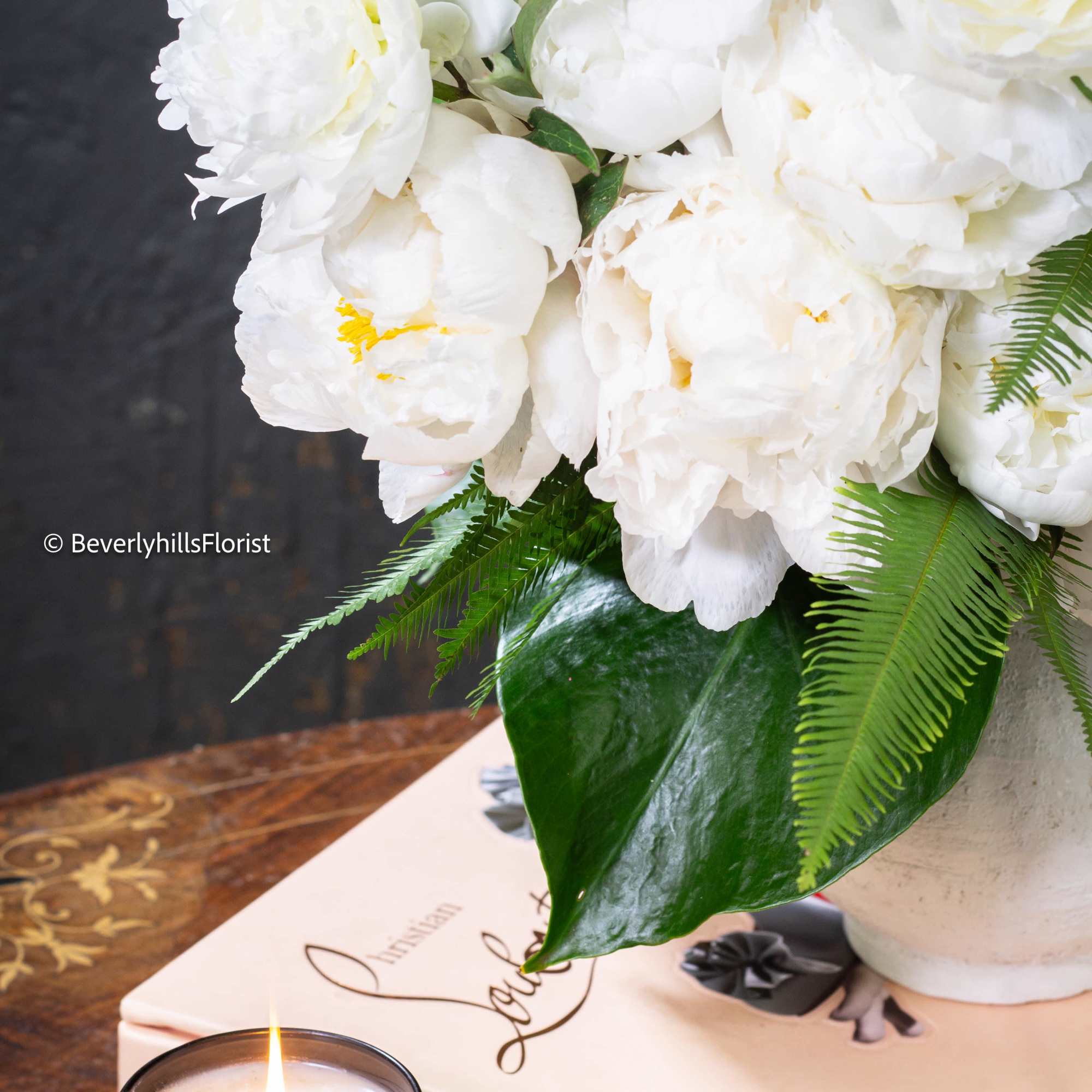  A lavish arrangement of over 20 pristine white peonies nestled within