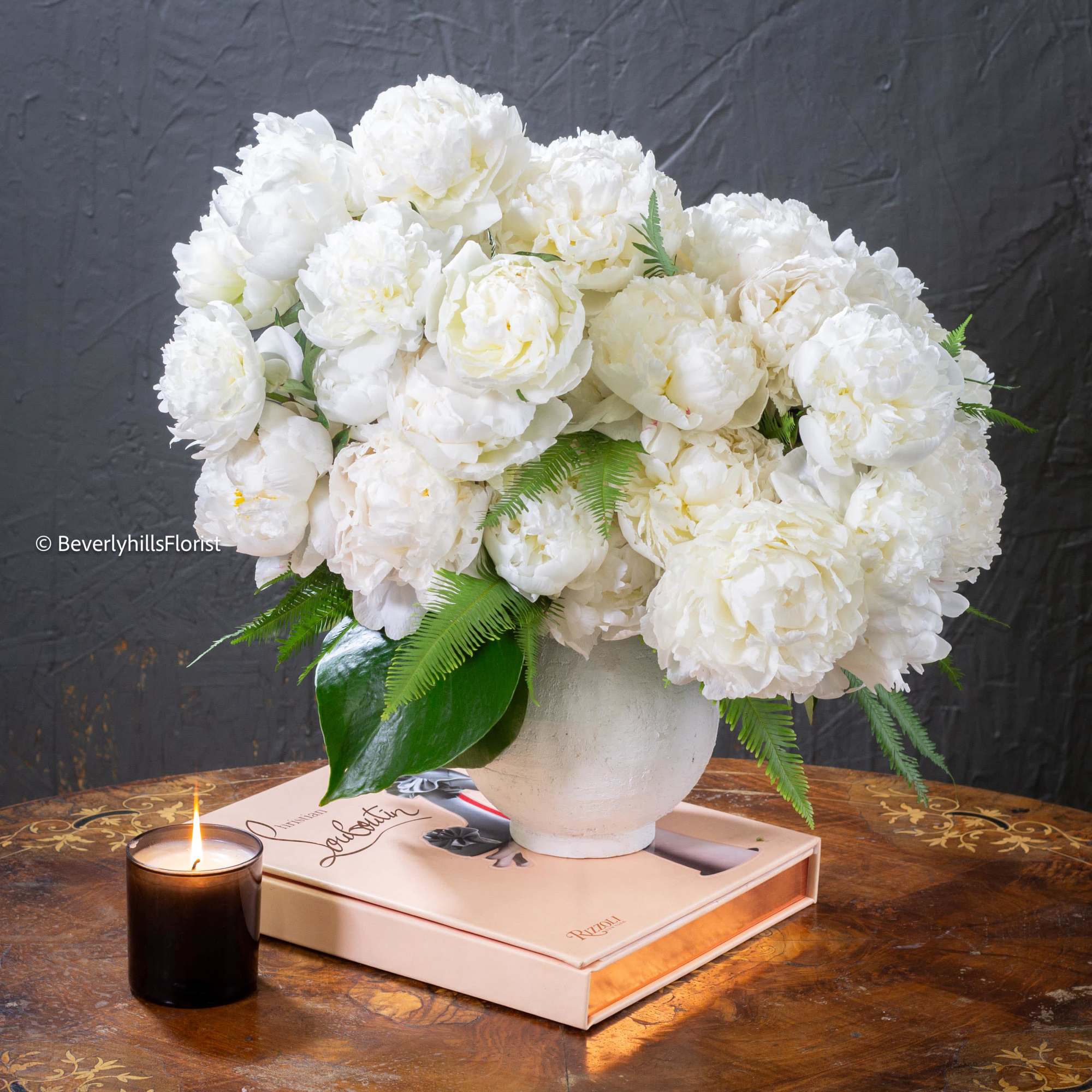  A lavish arrangement of over 20 pristine white peonies nestled within