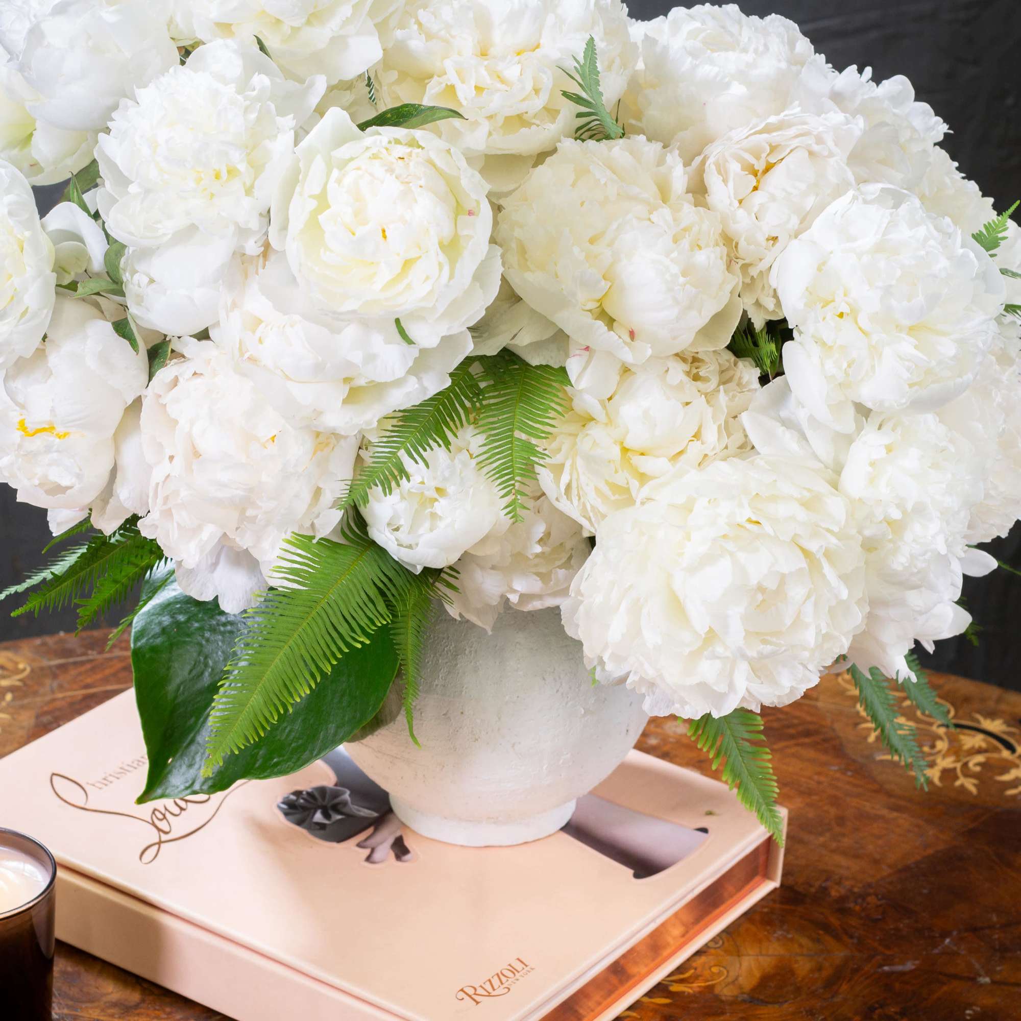  A lavish arrangement of over 20 pristine white peonies nestled within