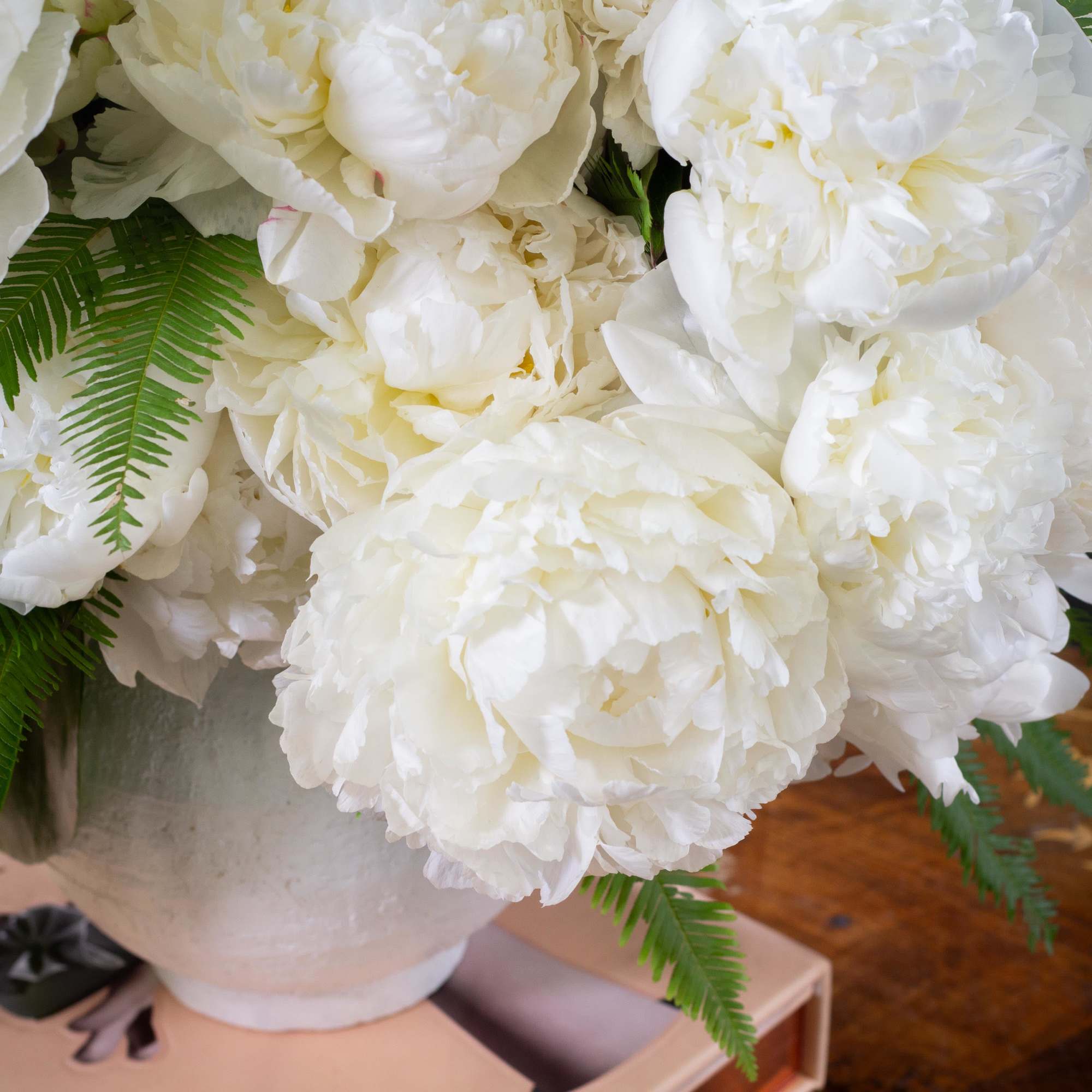  A lavish arrangement of over 20 pristine white peonies nestled within
