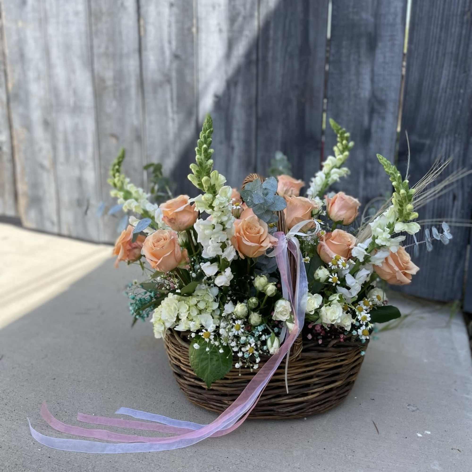 A charming garden-style arrangement featuring peach roses, snapdragons, chamomile, and more&mdash;designed in