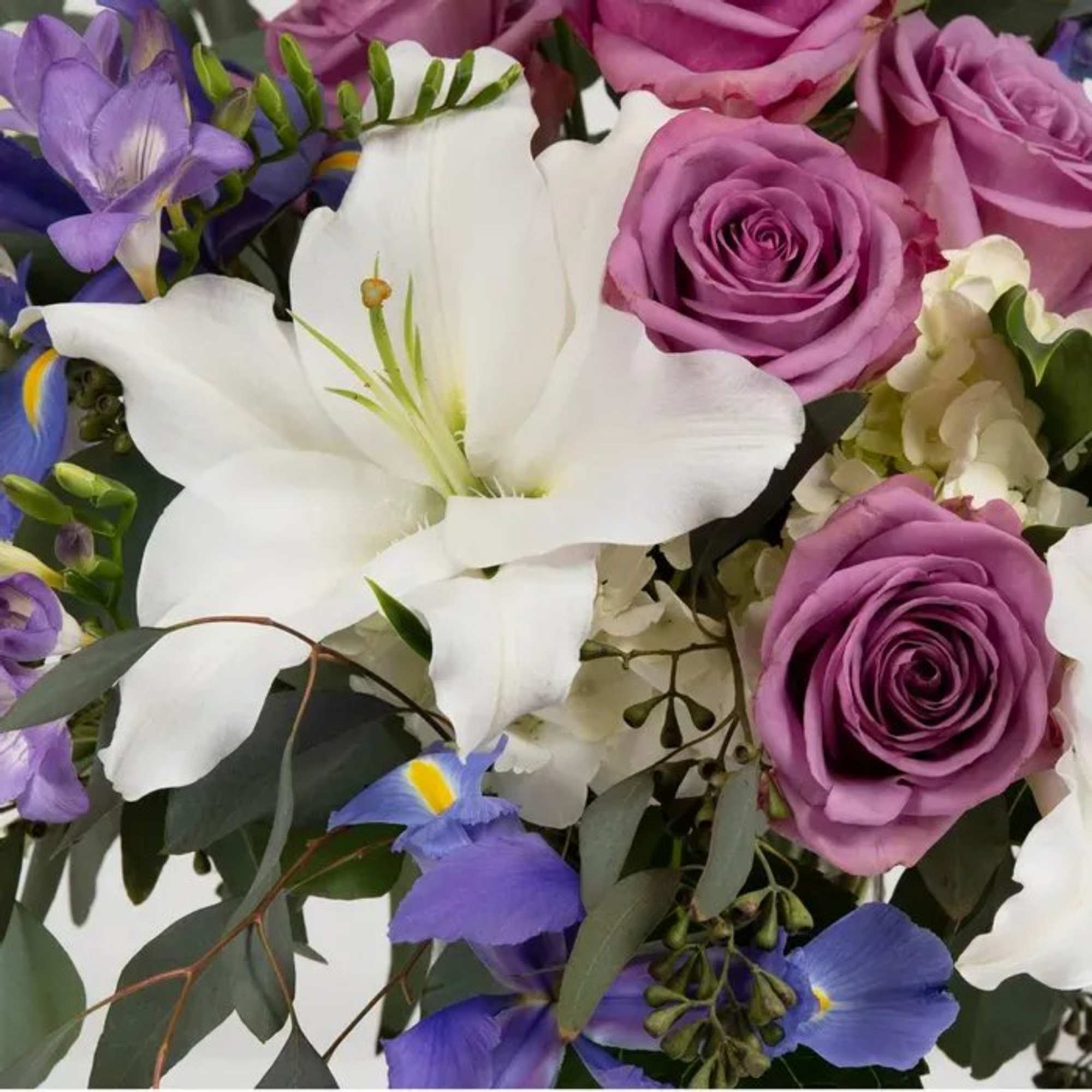 This arrangement of iris, delphinium, freesia, and asiatic lilies evokes a tranquil