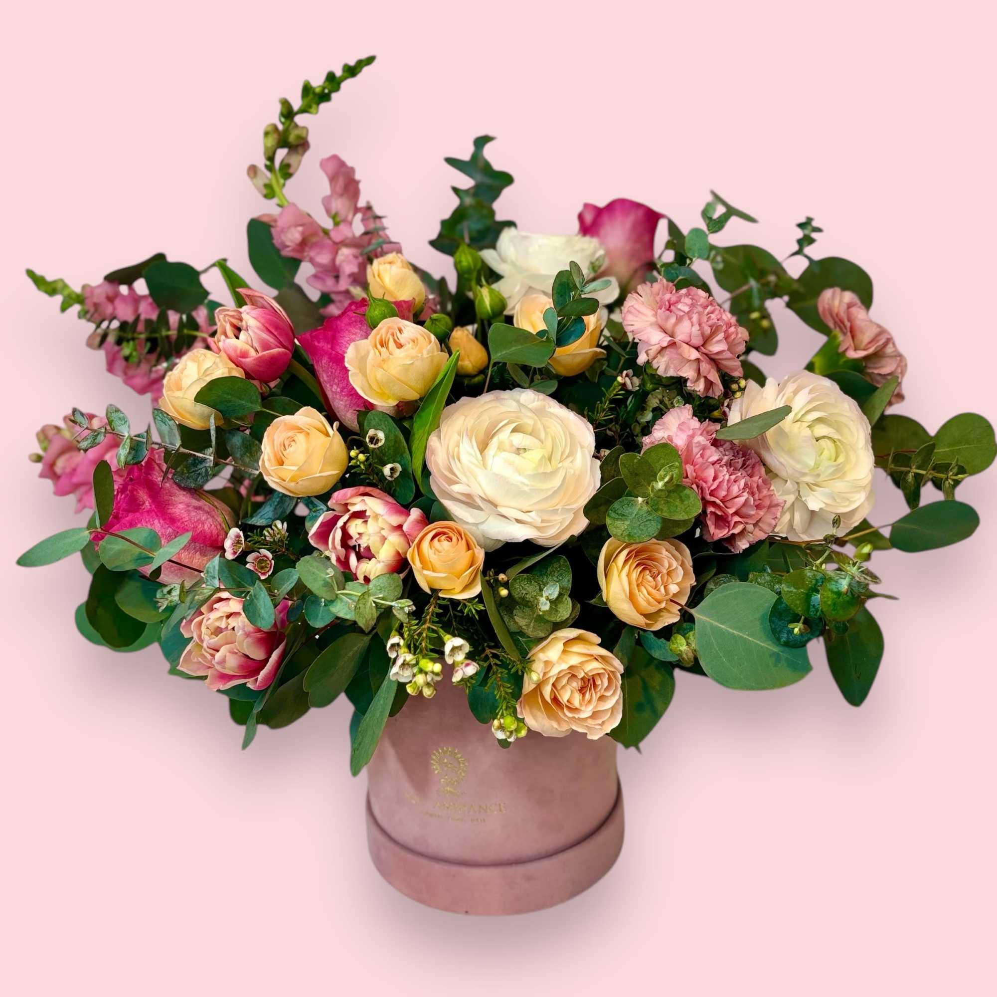 A fun and feminine arrangement of tulips, spray roses, and ranunculus. This