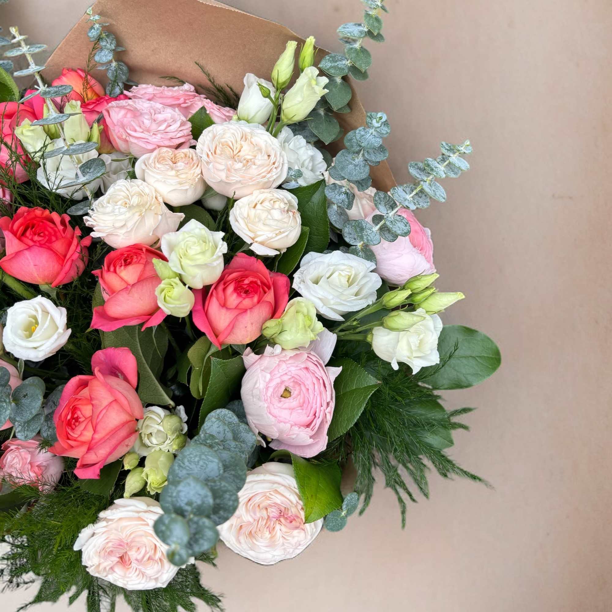 Bouquet made of an array of spray roses, ranunculus, and lisianthus .