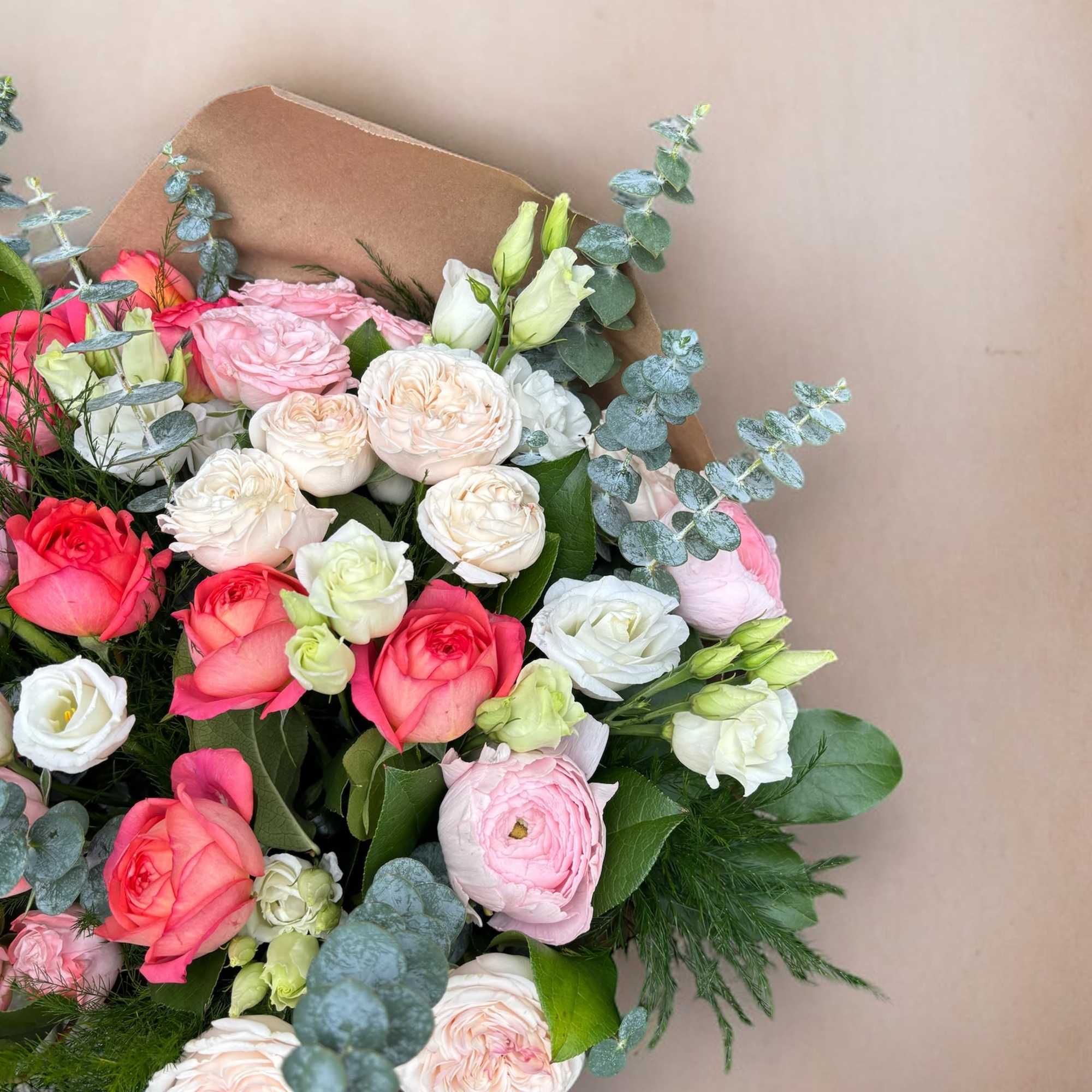 Bouquet made of an array of spray roses, ranunculus, and lisianthus .
