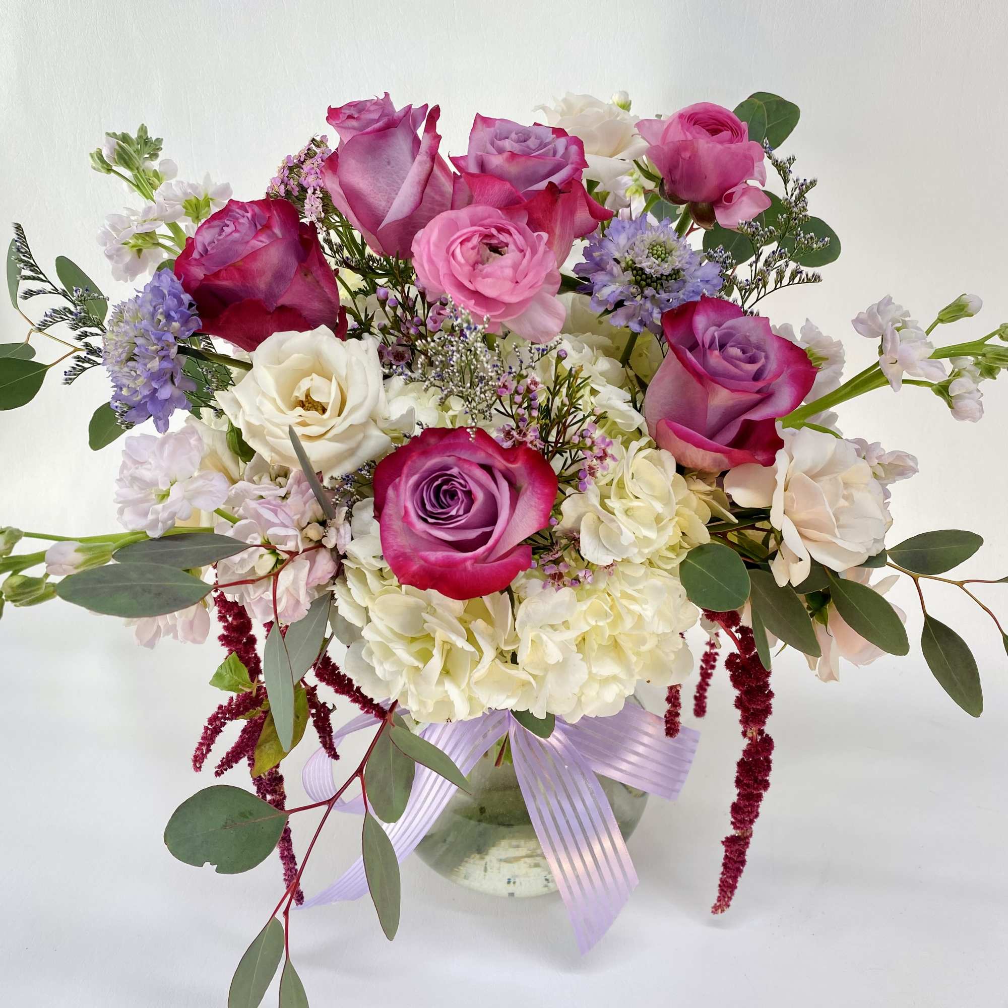 Deep purple roses, white hydrangeas, soft lilac stocks, pink ranunculus and other