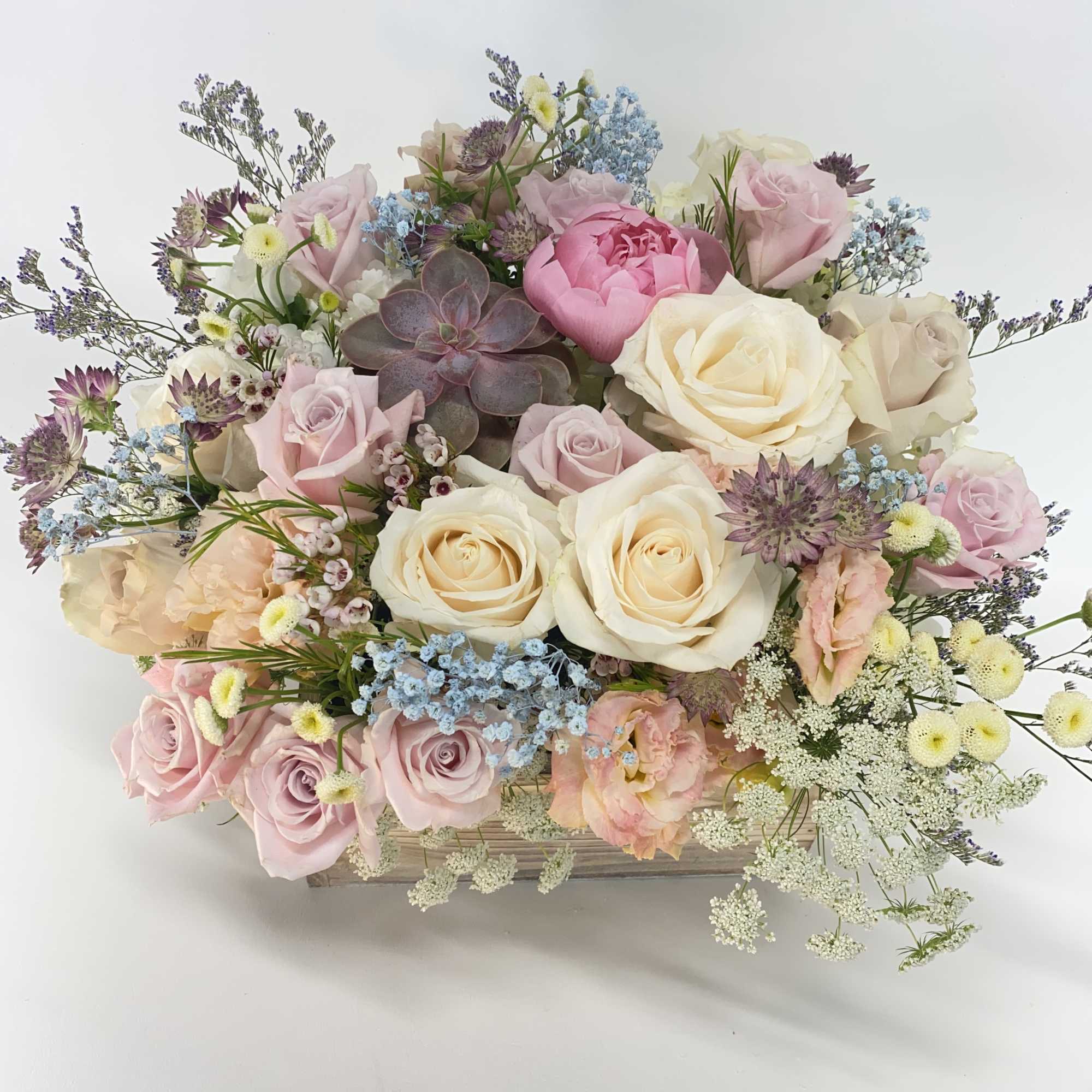 Square wooden box filled with all pastel flowers. 