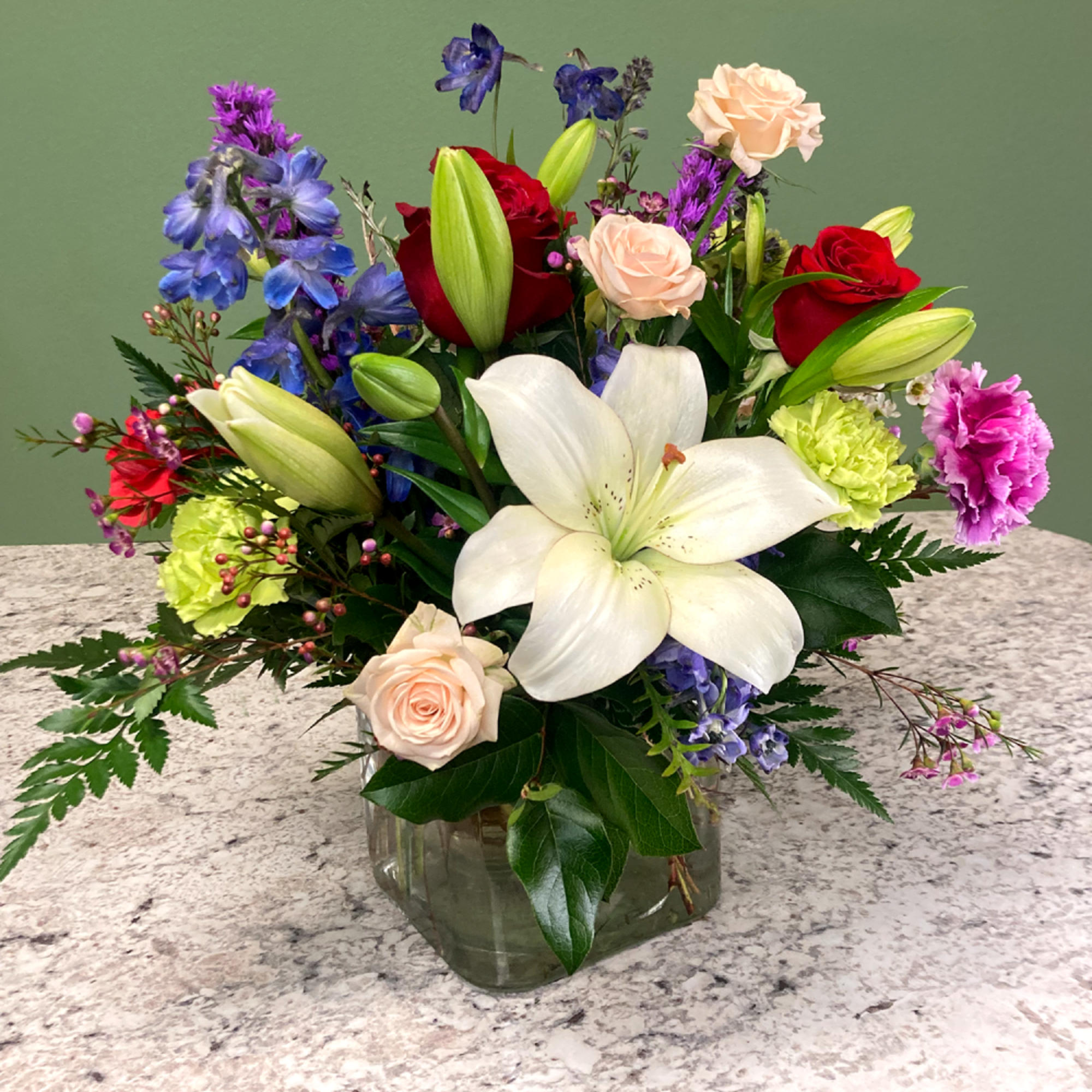 A sleek mixed arrangement that showcases vibrant Spring colors, featuring roses, astatic