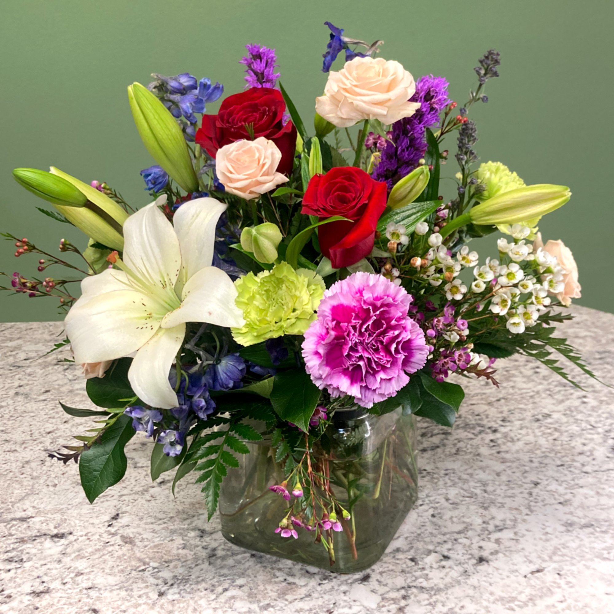 A sleek mixed arrangement that showcases vibrant Spring colors, featuring roses, astatic