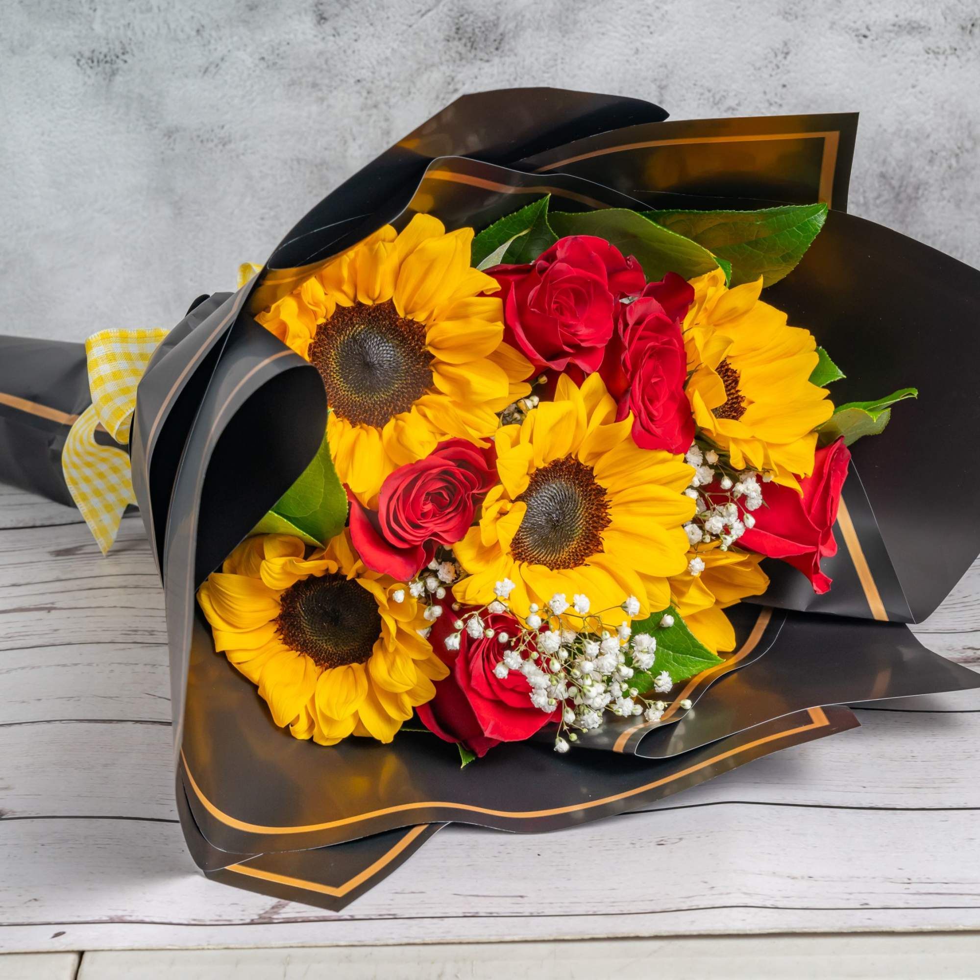 A cheerful wrapped bouquet featuring vibrant sunflowers
paired with elegant roses, creating a