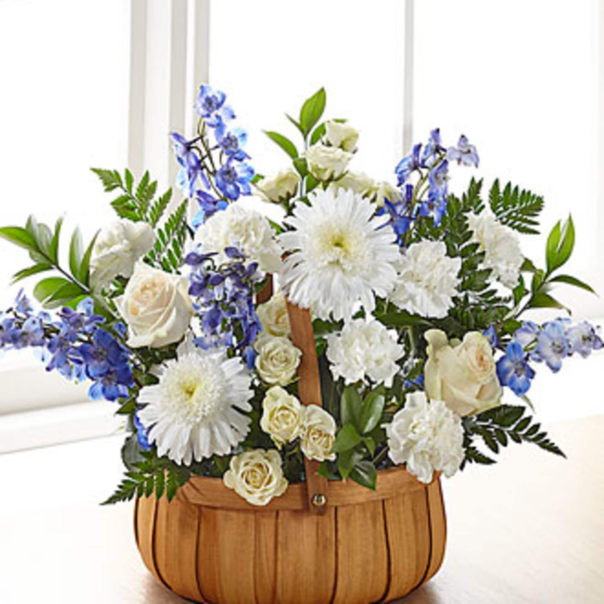 This basket arrangement has blue and white flowers such as delphinium, spray