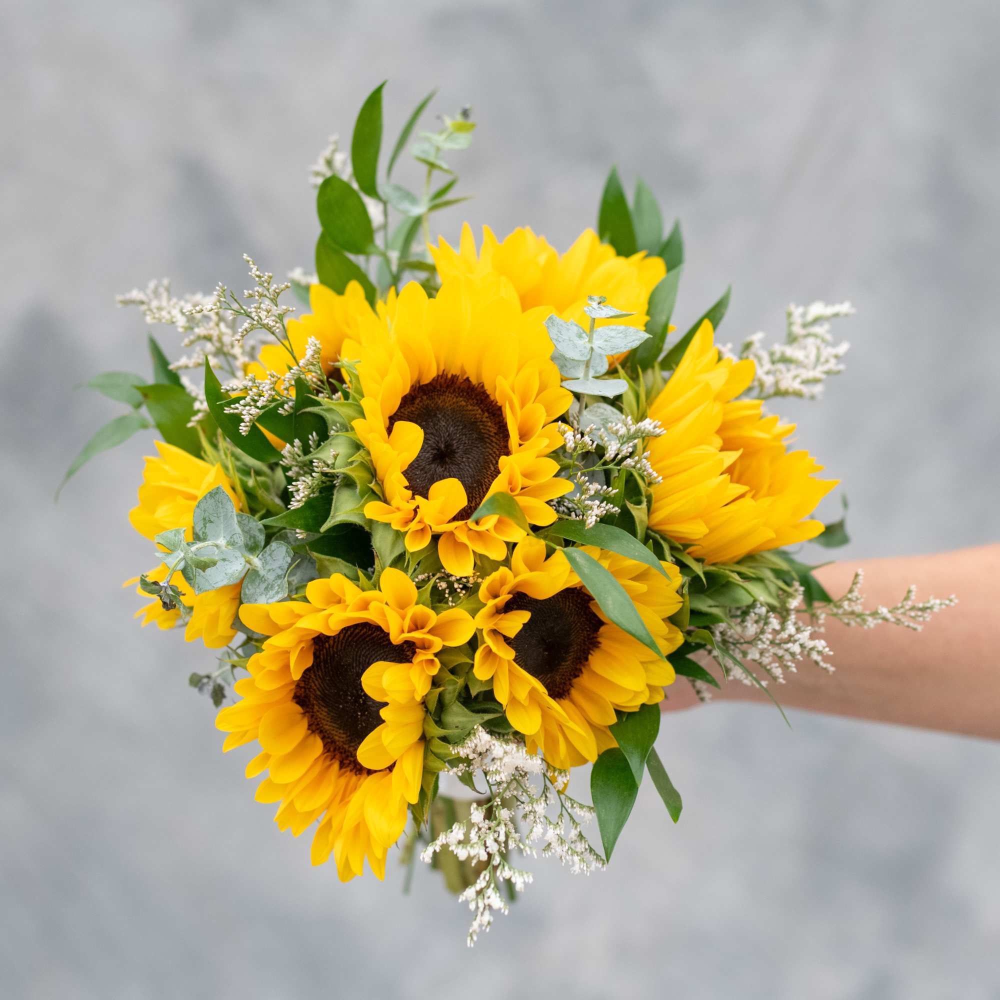 Bright and beautiful sunflowers mixed with delicate greenery and white accented flowers.