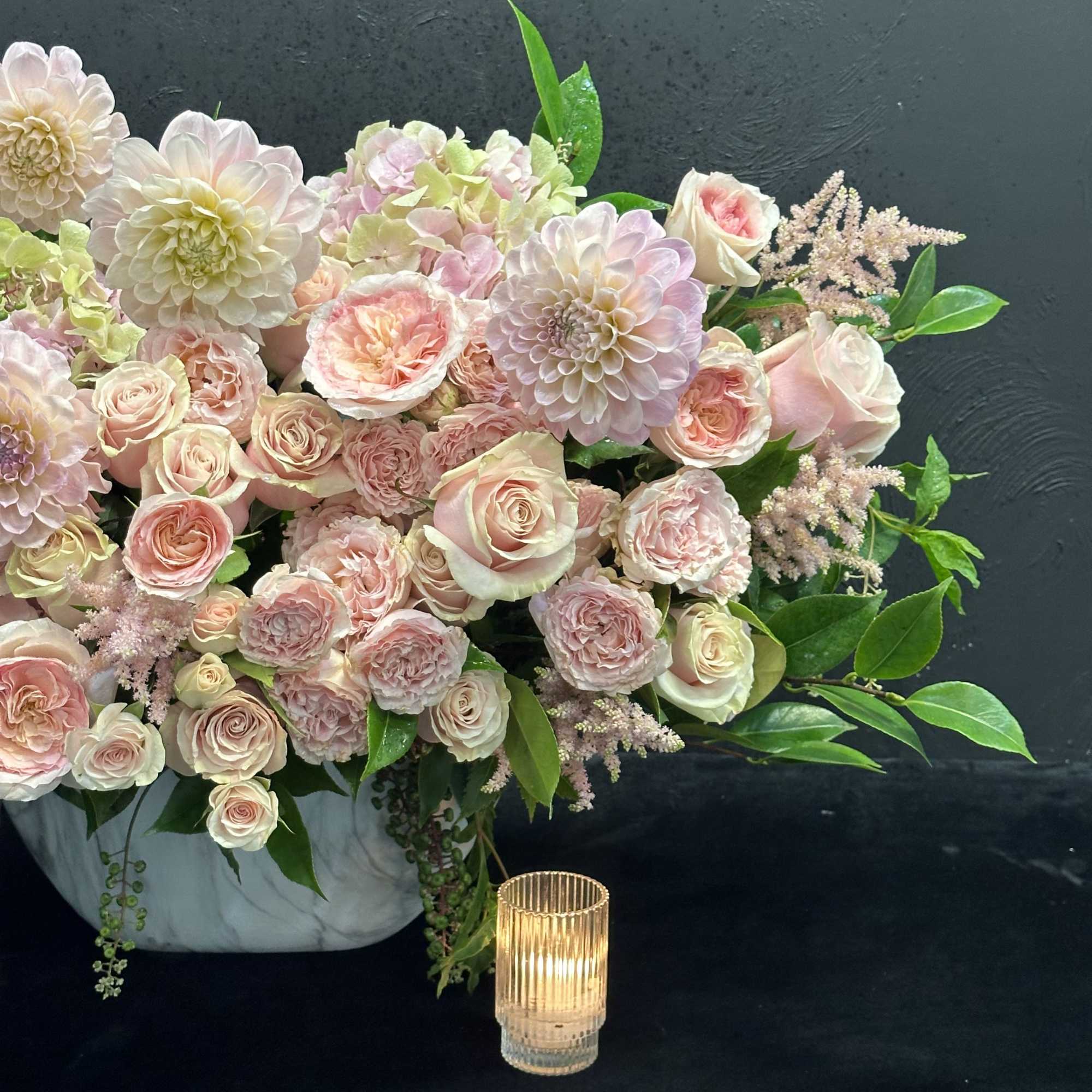 This lovely arrangement features a delightful mix of pastel dahlias, garden roses