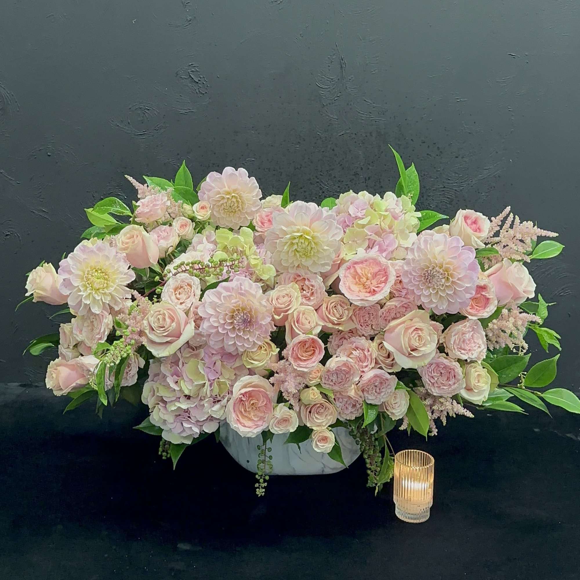 This lovely arrangement features a delightful mix of pastel dahlias, garden roses