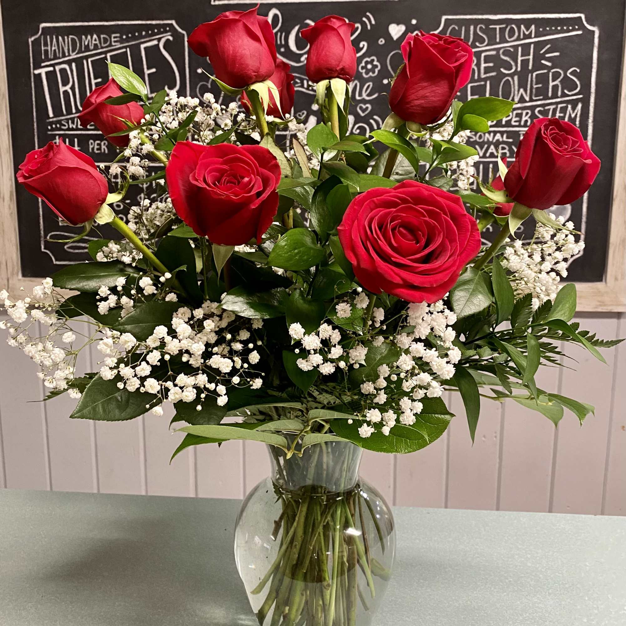 One dozen red roses, baby's breath and greenery in a vase One dozen red roses, baby's breath and greenery in a vase