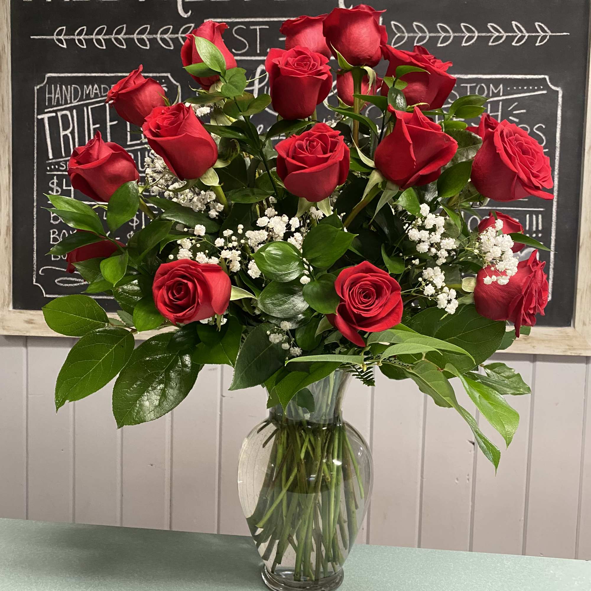 One dozen red roses, baby's breath and greenery in a vase One dozen red roses, baby's breath and greenery in a vase