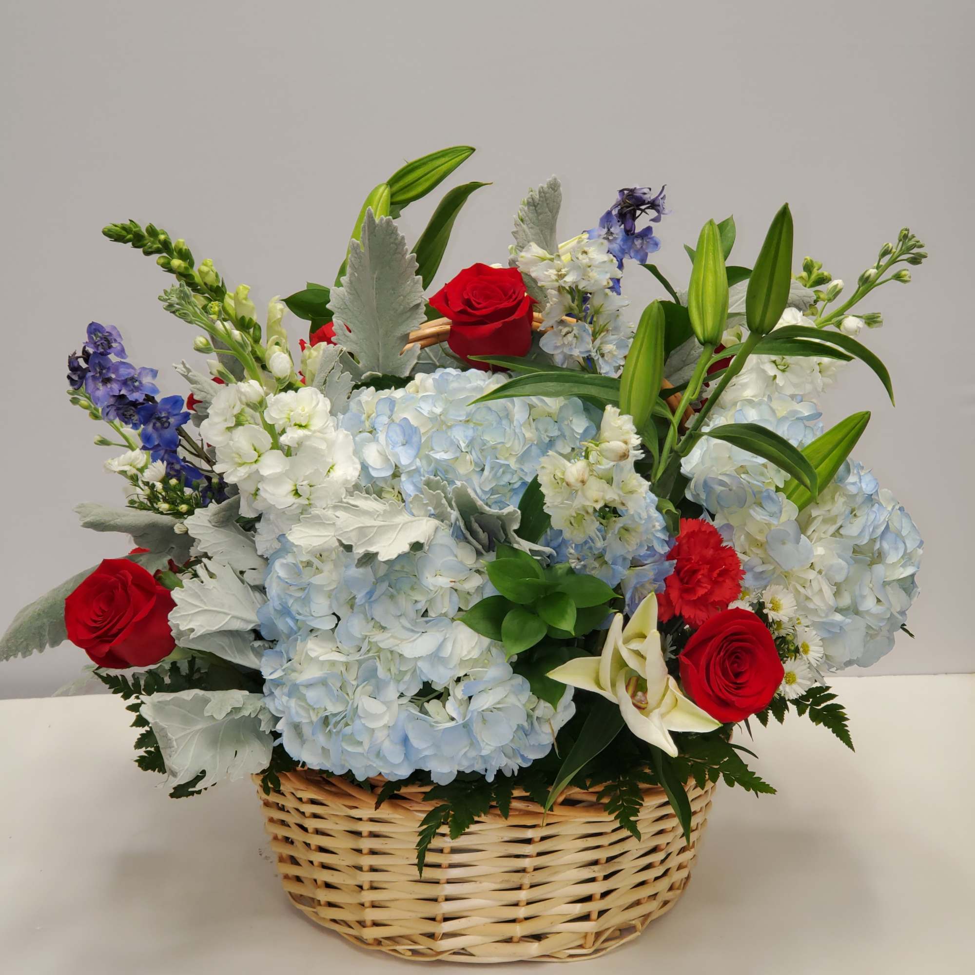 7 red roses, 5 red carnations, 4 blue hydrangea, 4 blue delphinium