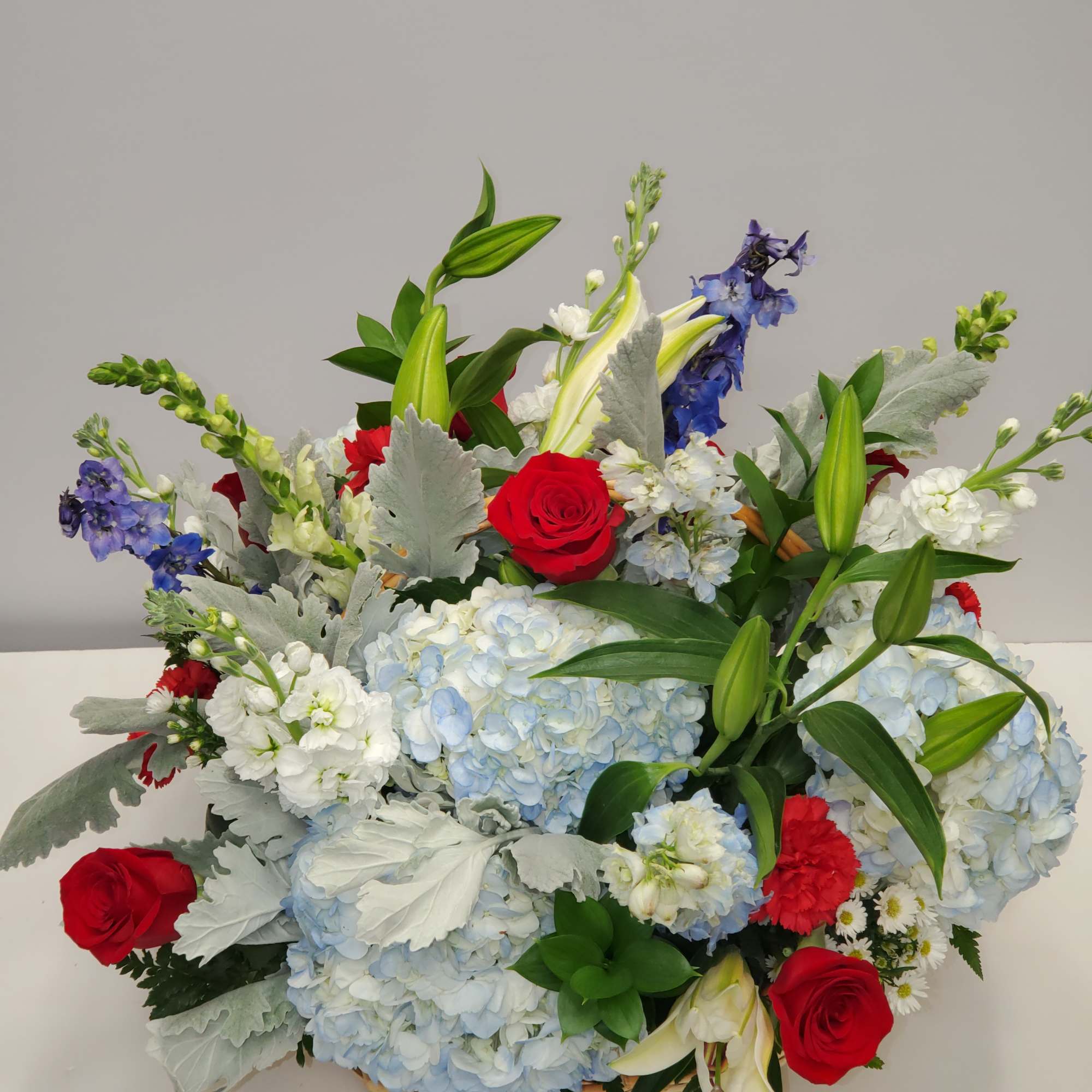 7 red roses, 5 red carnations, 4 blue hydrangea, 4 blue delphinium