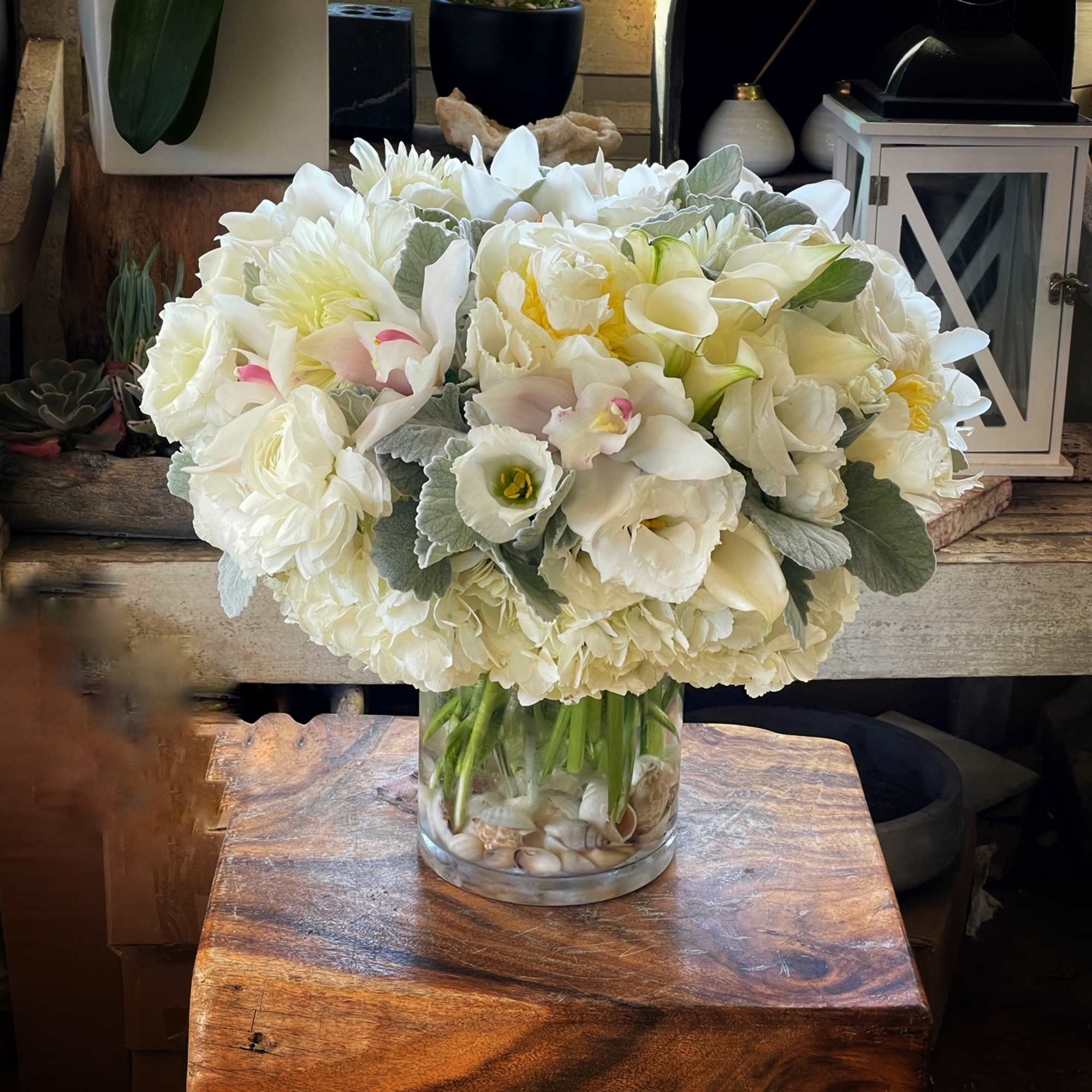 Hydrangeas, Cymbidium Orchid and green leaves in cylinder vase.