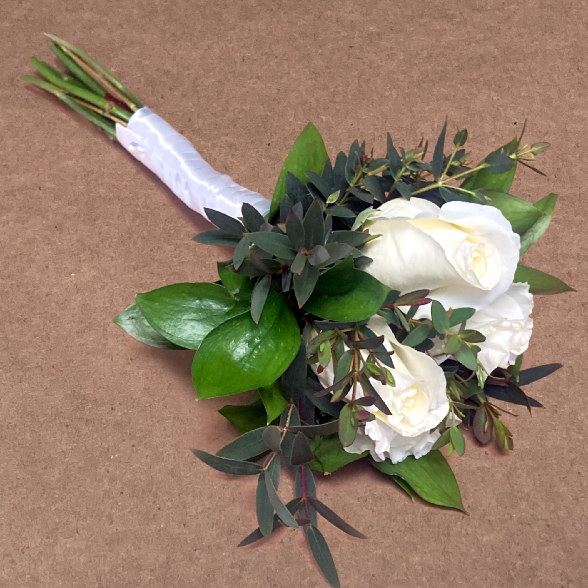 A slender, fragrant bouquet featuring roses and freshly-cut greens. Hand-tied with decorative
