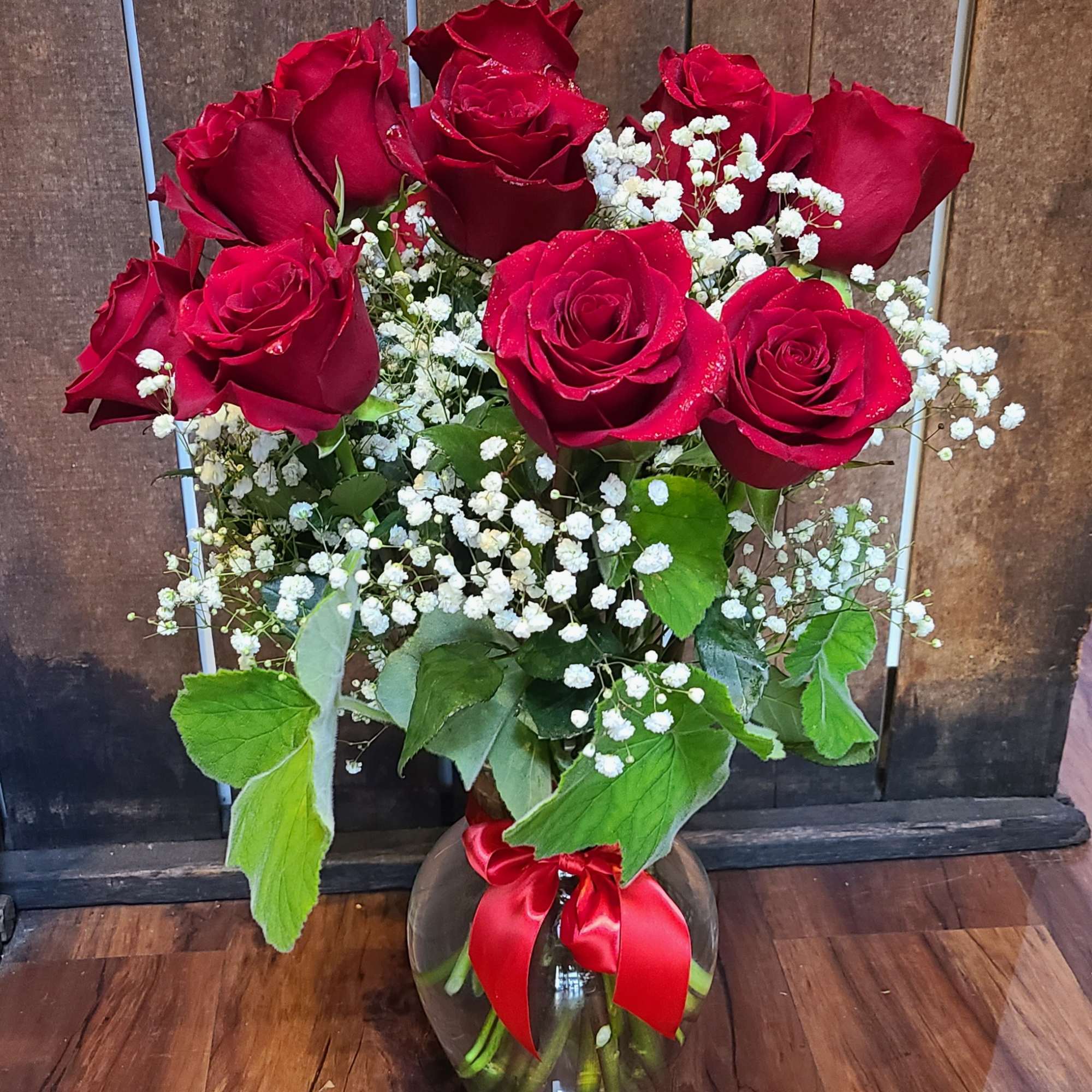 A dozen red roses, designed with babies breath and mixed foliage arranged