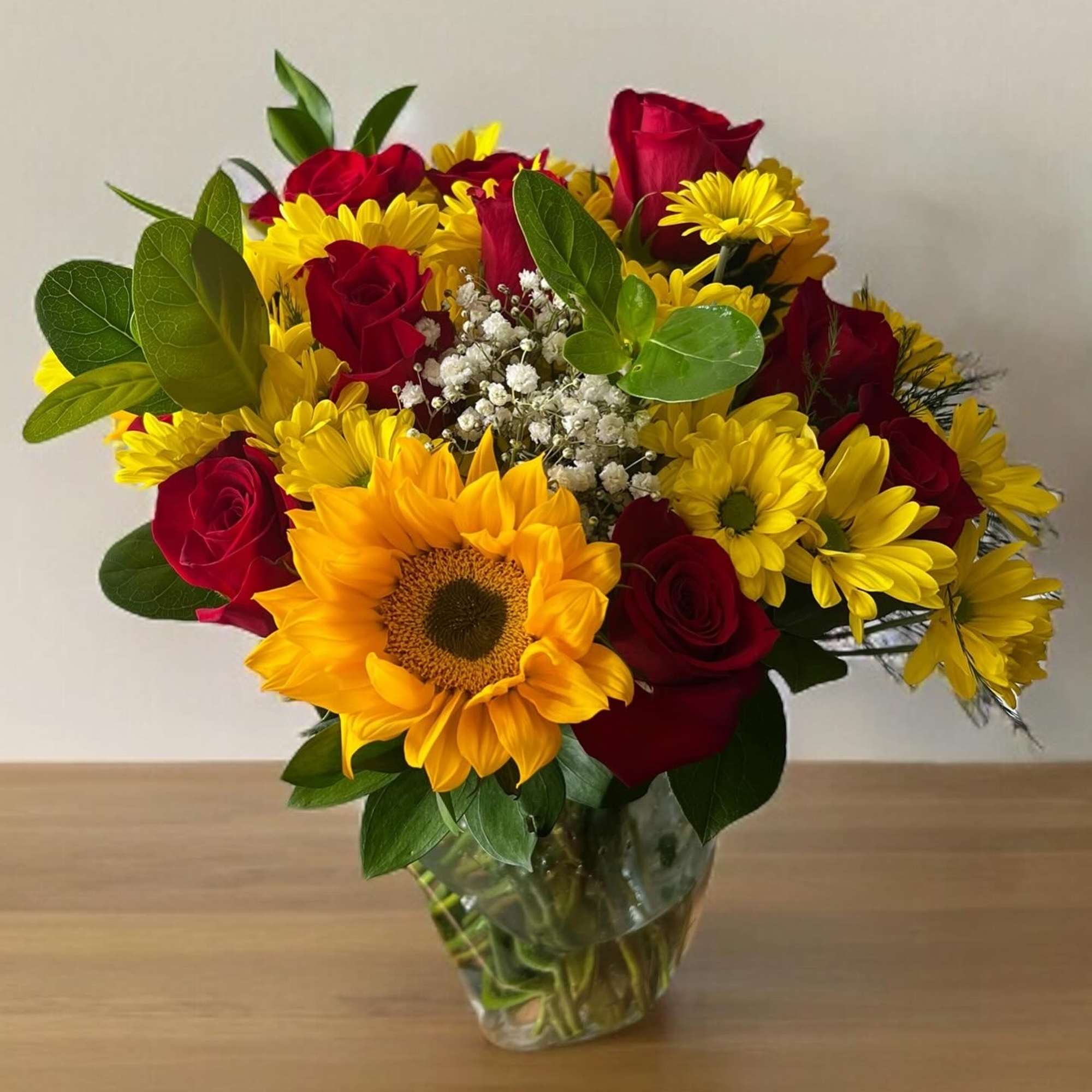 This bouquet features classic red roses and sunflowers with a mix of
