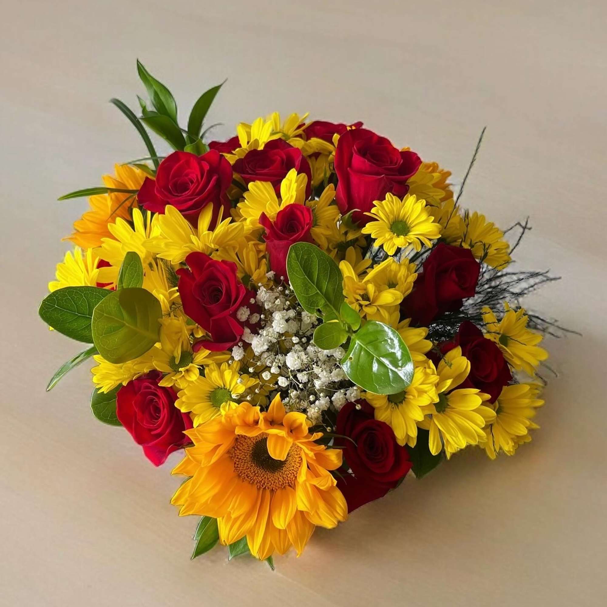 This bouquet features classic red roses and sunflowers with a mix of