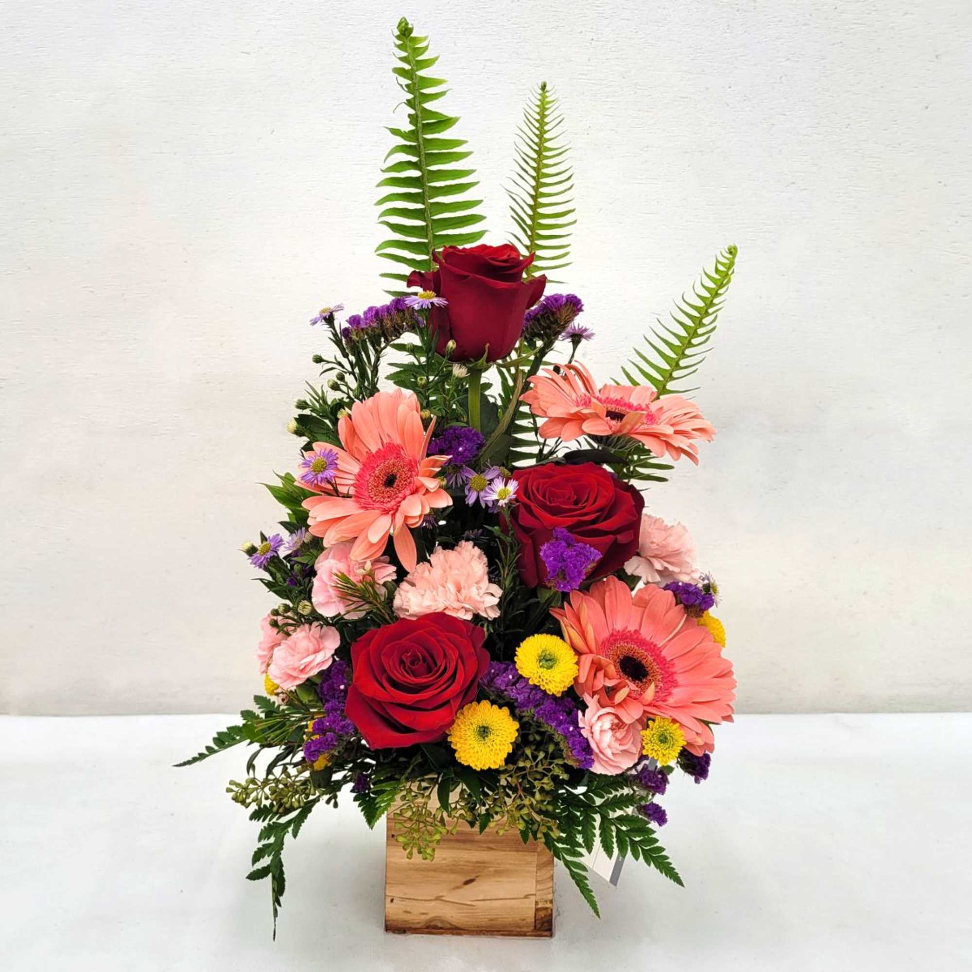 A beautiful arrangement of flowers in a rustic wooden cube overflowing with