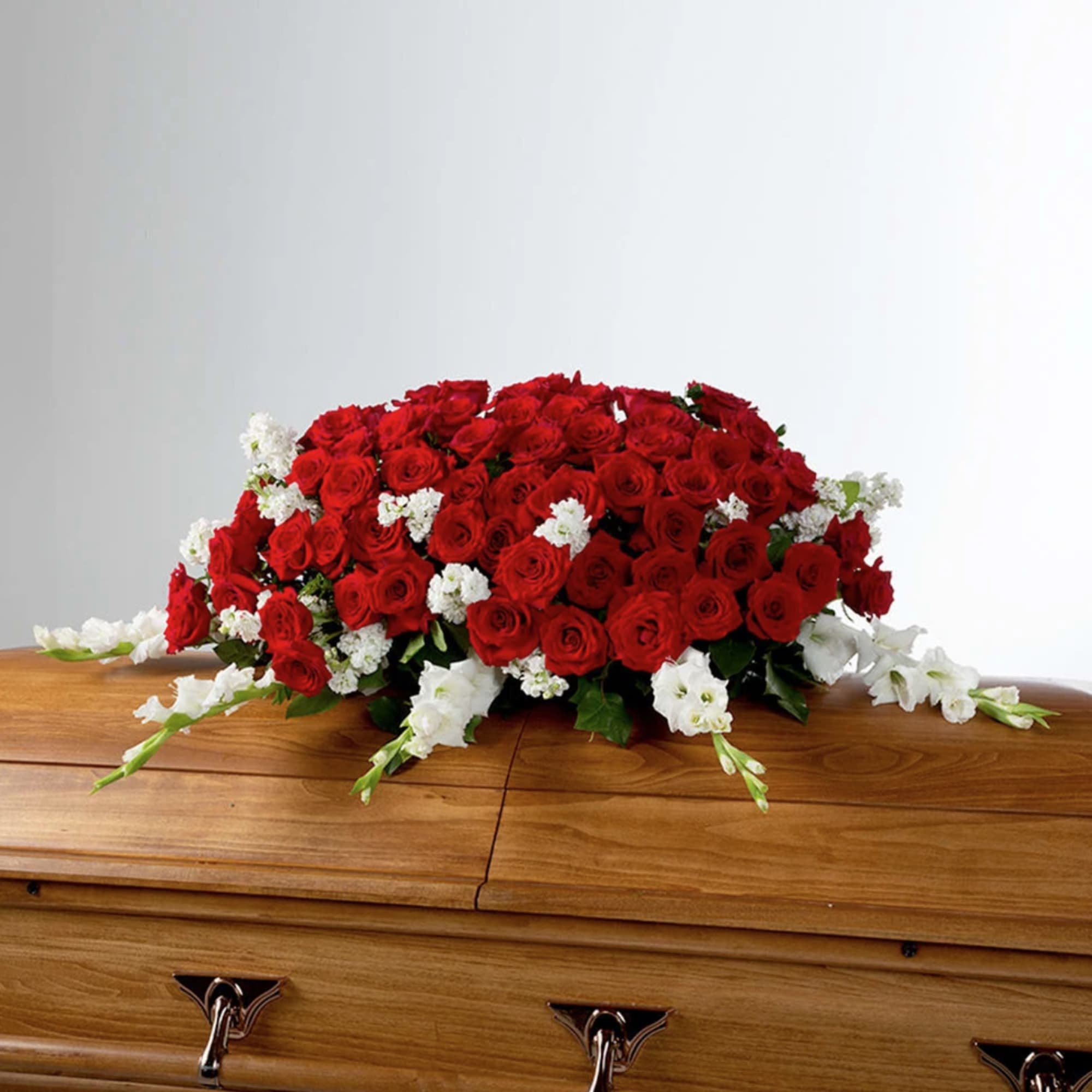 Red roses and white flowers in this full casket symbolize love and