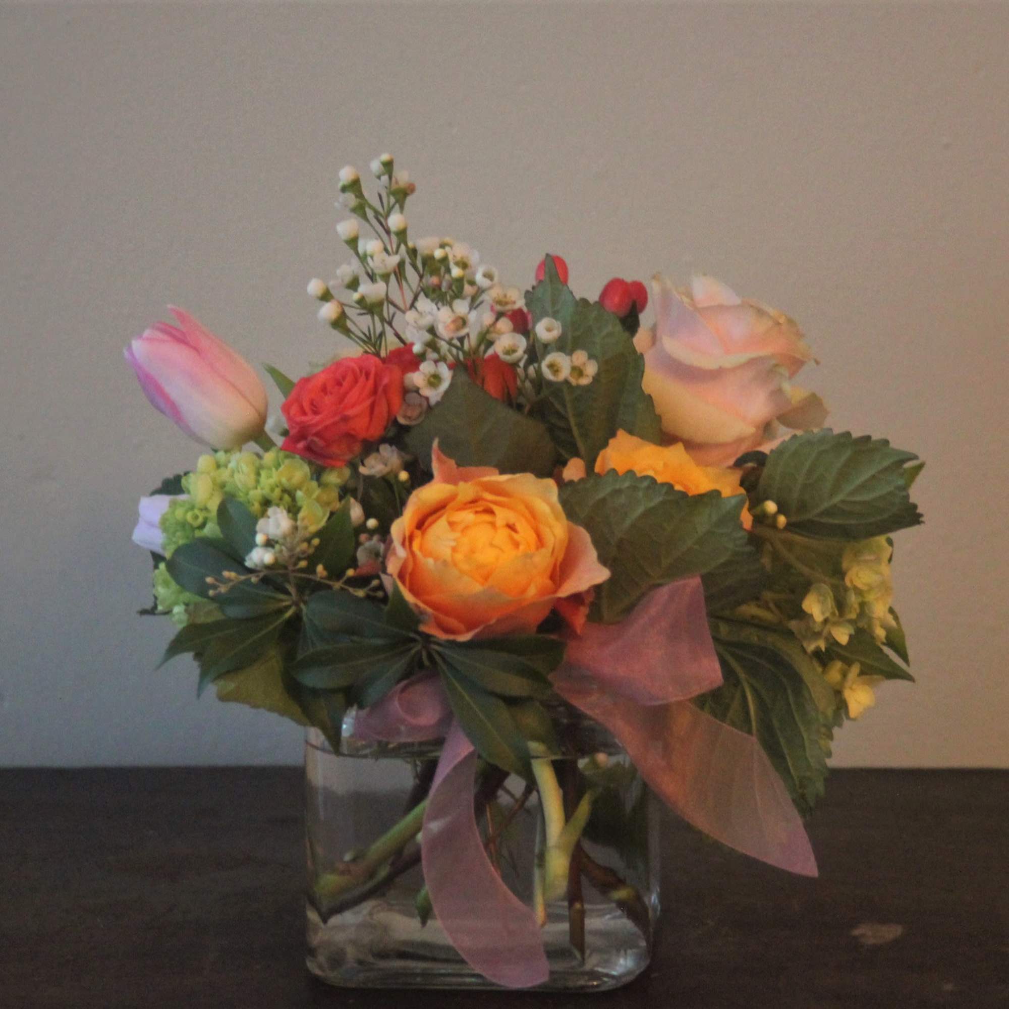 A cheerful assortment of pink roses, orange roses, spray roses, green hydragea