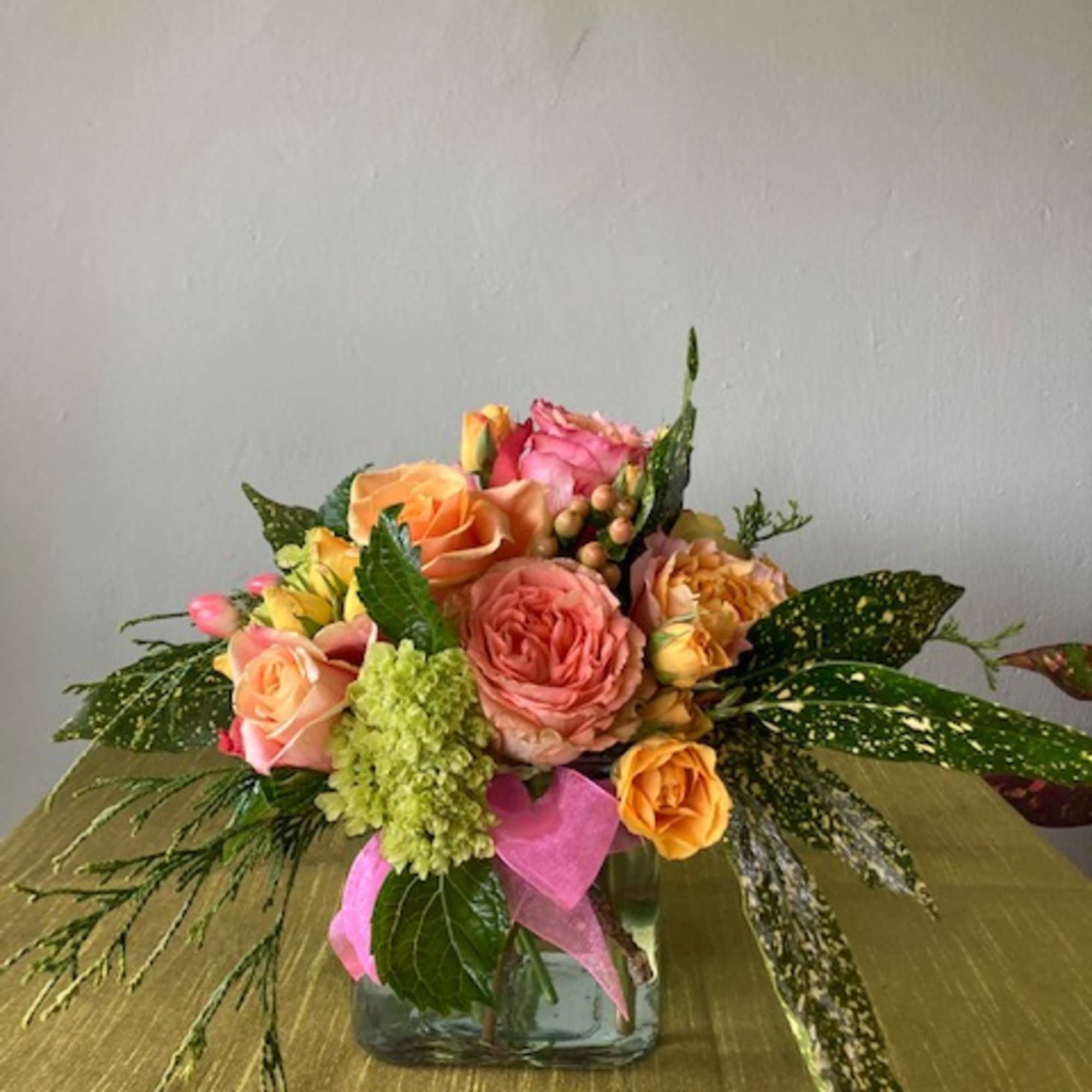A cheerful assortment of pink roses, orange roses, spray roses, green hydragea