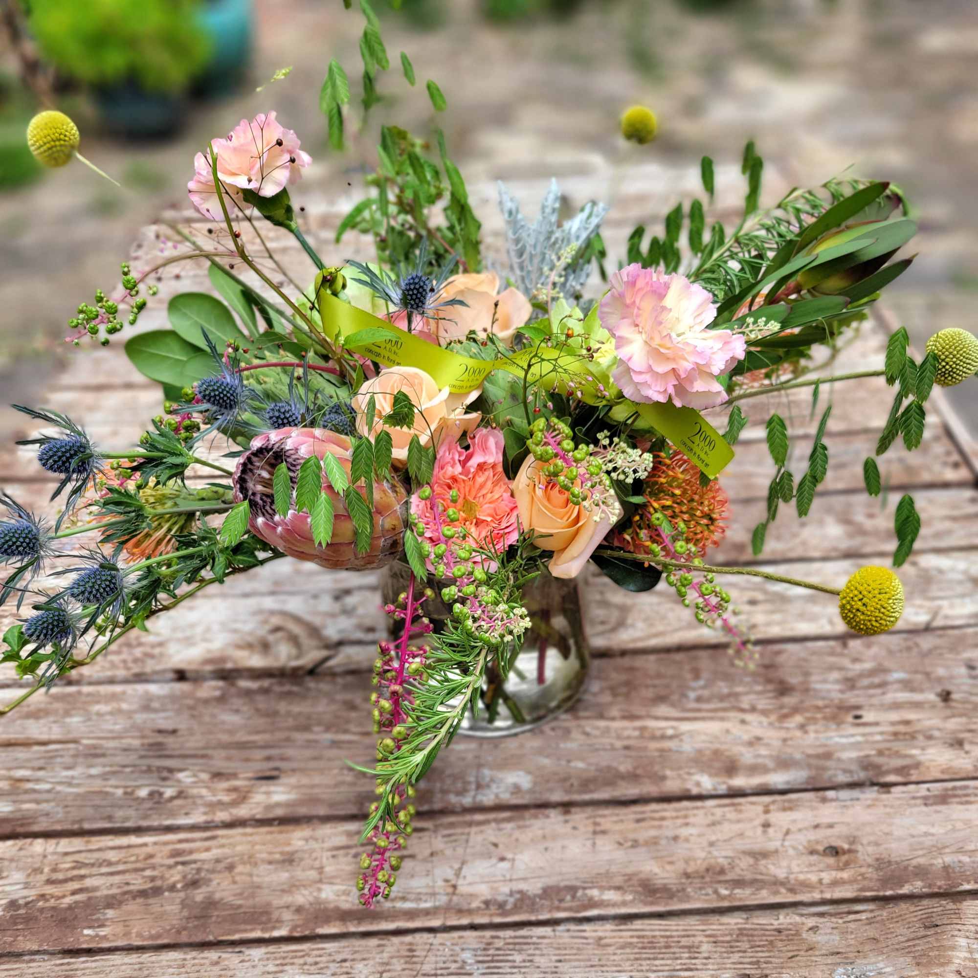 An eclectic beauty containing assorted seasonal blooms, berries, pods and assorted garden