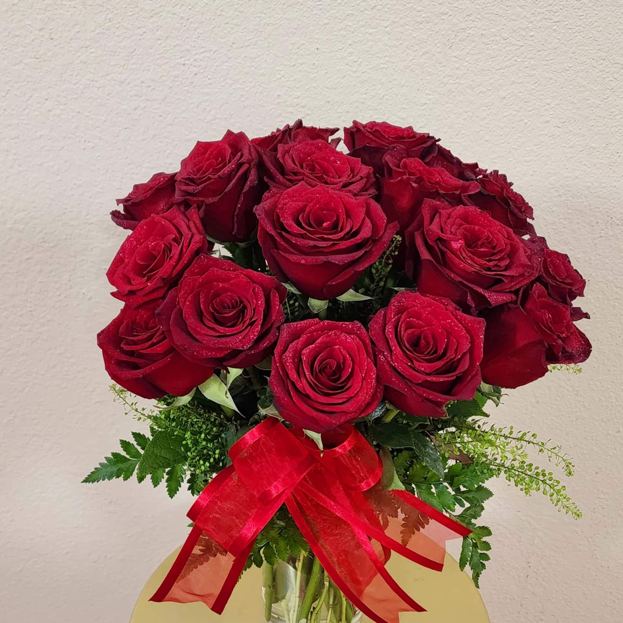18 premium Ecuadorian roses with a bright red ribbon on it.