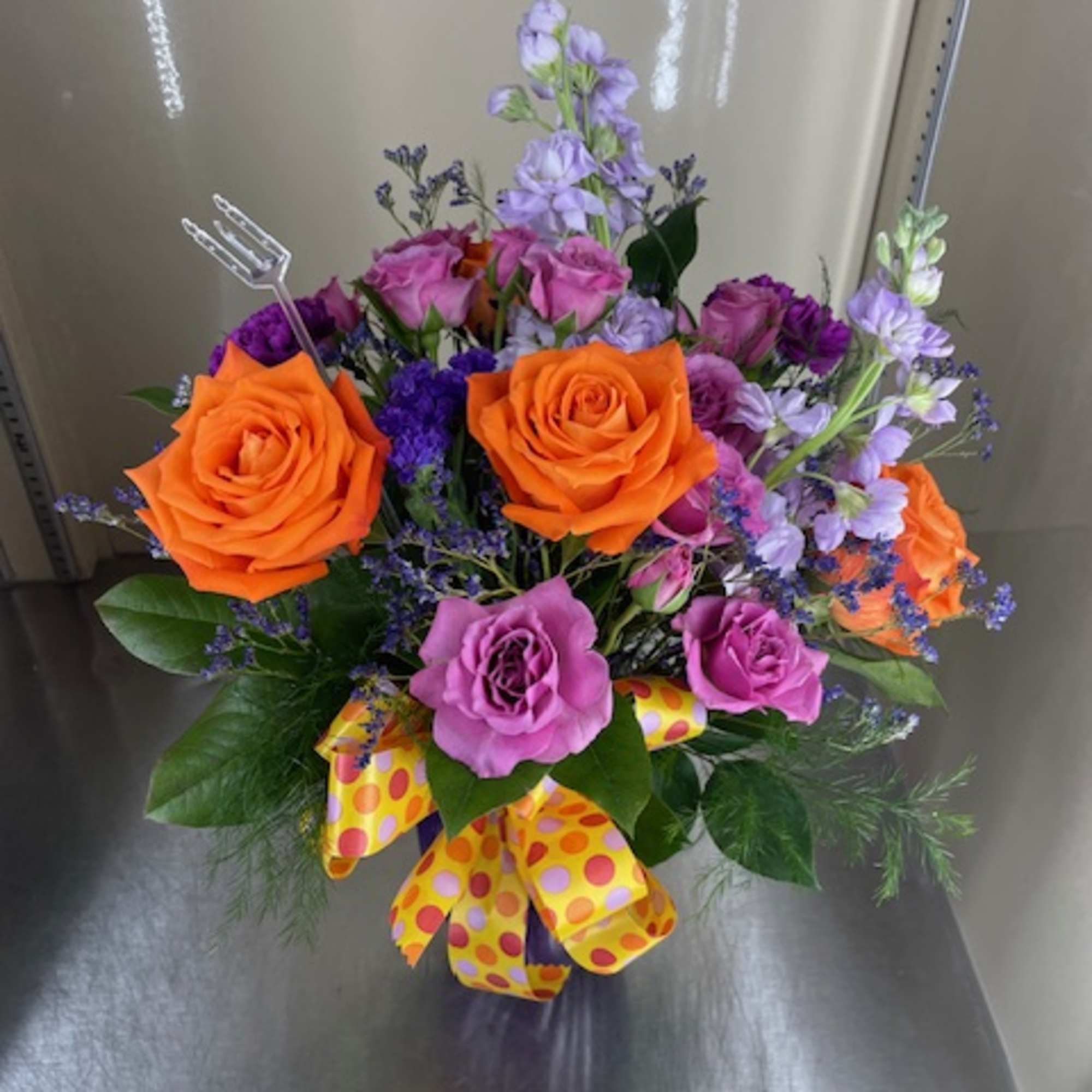 Mixed cut flowers with orange roses, lavender stock, purple carnations, purple spray