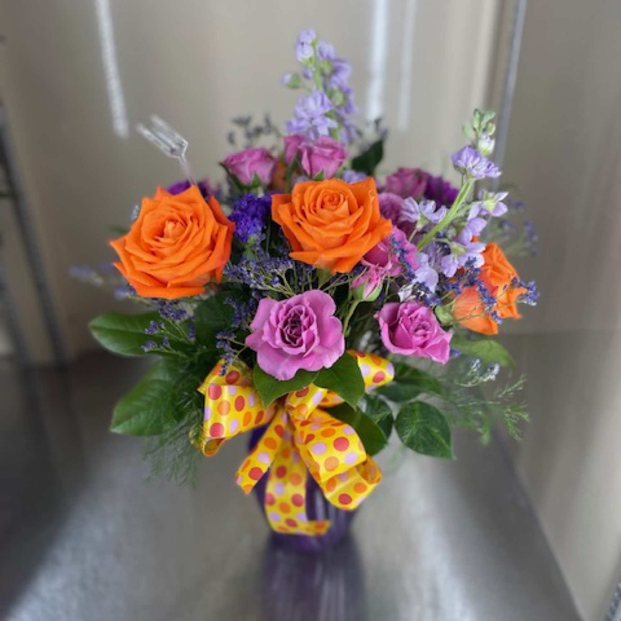 Mixed cut flowers with orange roses, lavender stock, purple carnations, purple spray