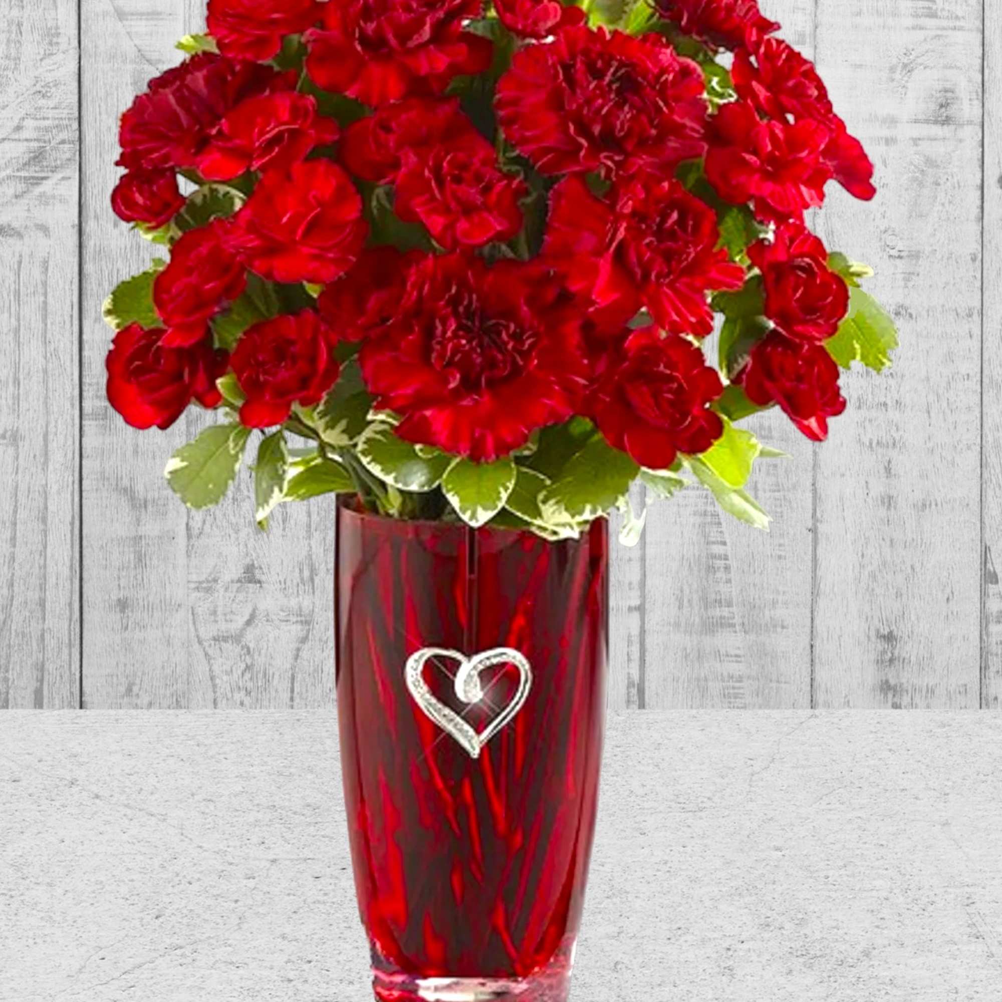 This vase includes a brilliant burst of red carnations and beautiful greens.