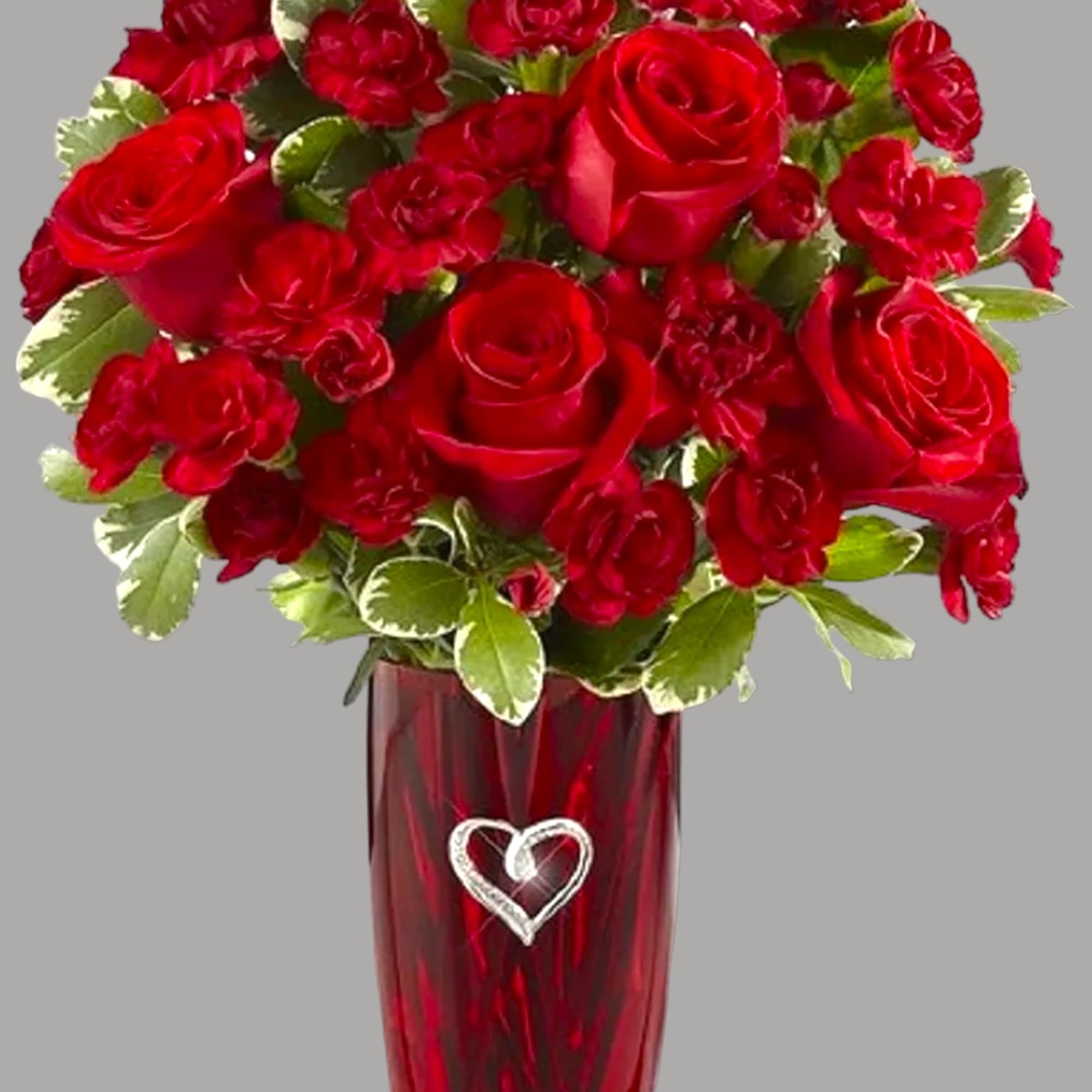 This vase includes a brilliant burst of red carnations and beautiful greens.