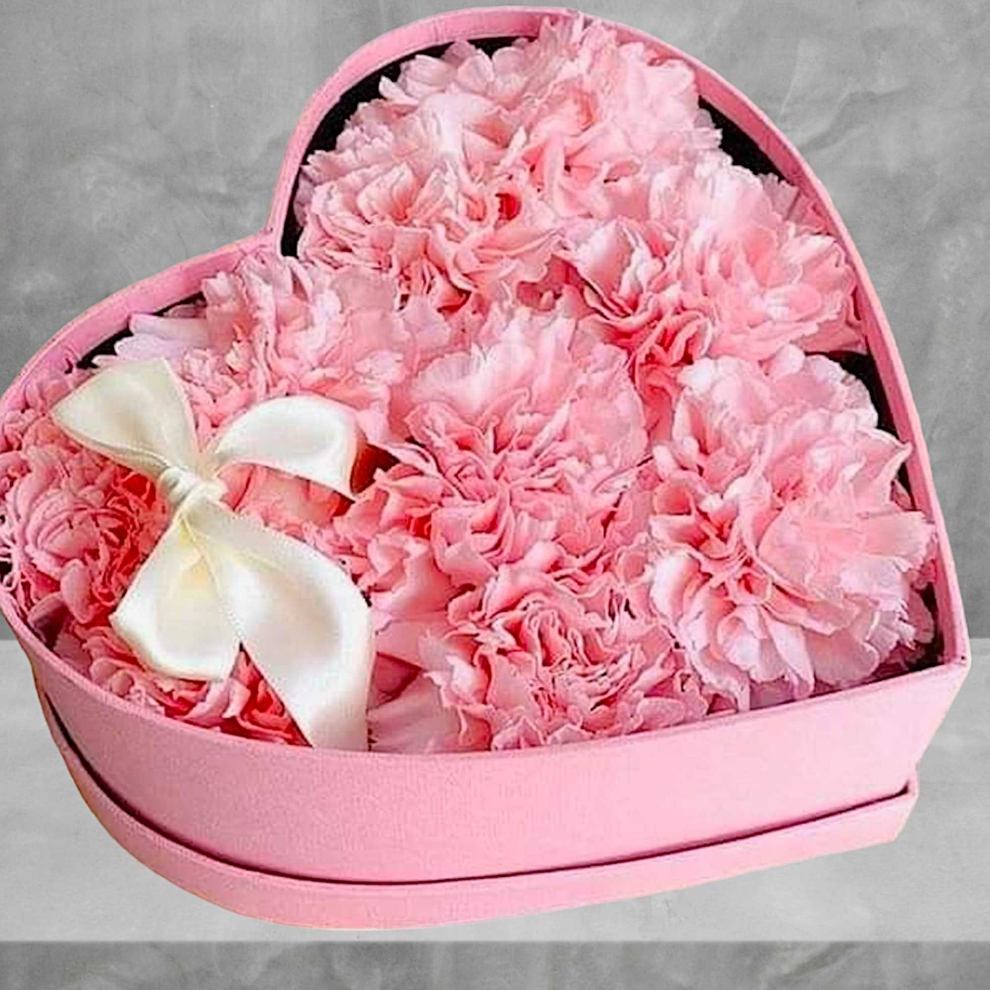 A modern flower arrangement in a heart box filled with pink carnations.