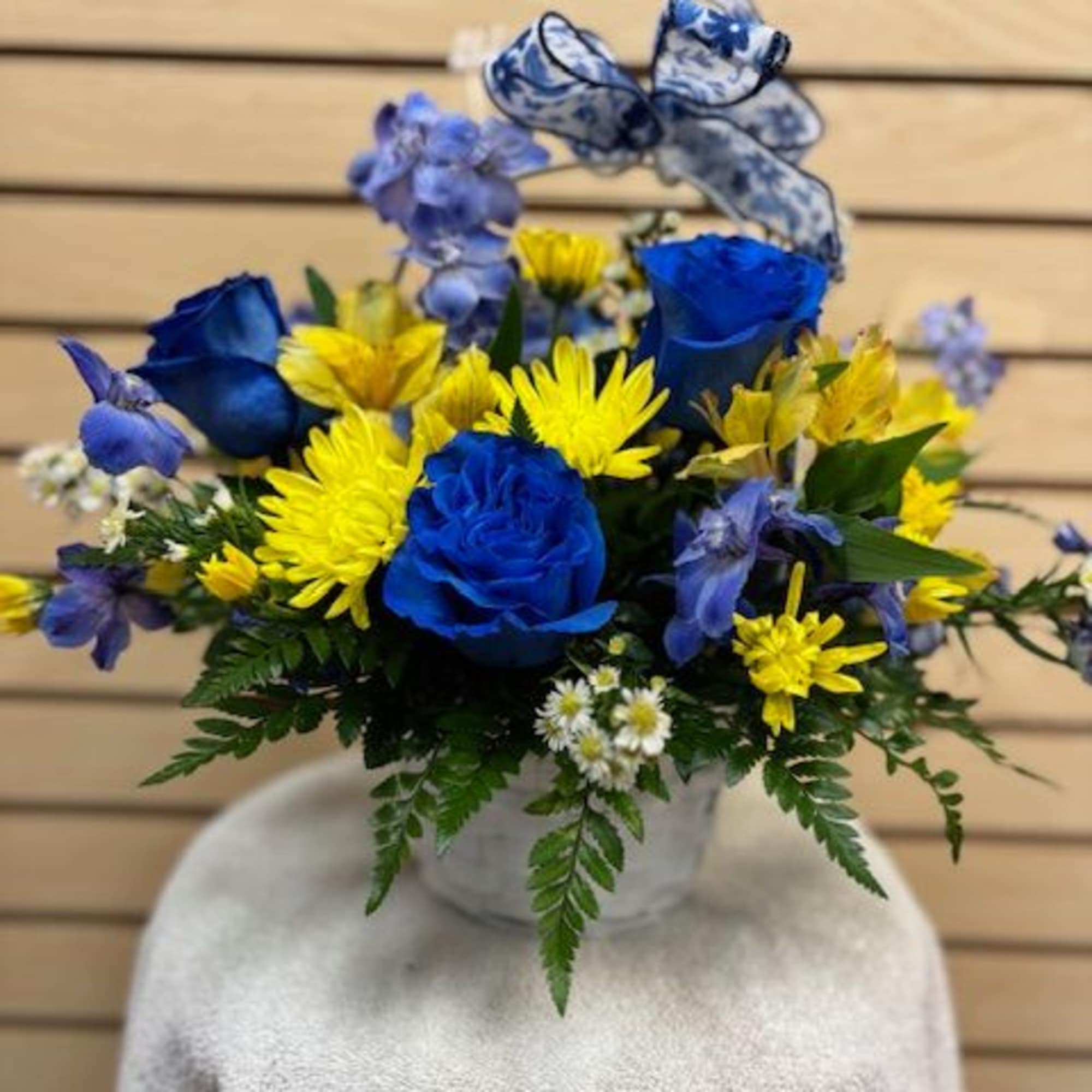 Mixed cut with blue roses, yellow cushions, blue delphinium, and white monte