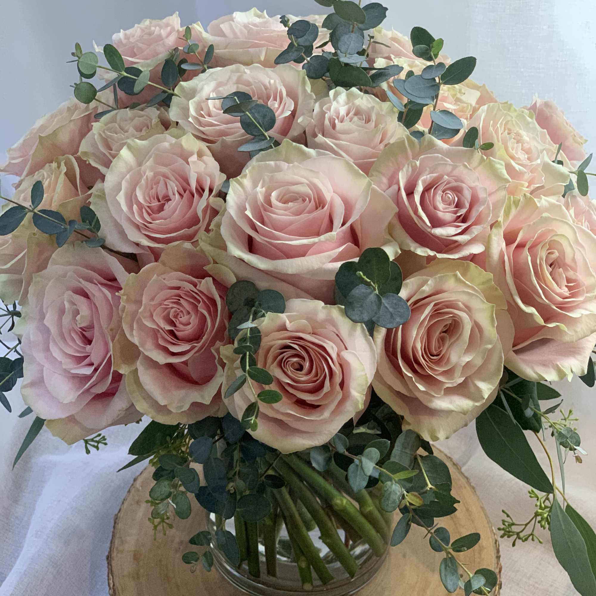 Blush pink roses and eucalyptus in a clear vase. 